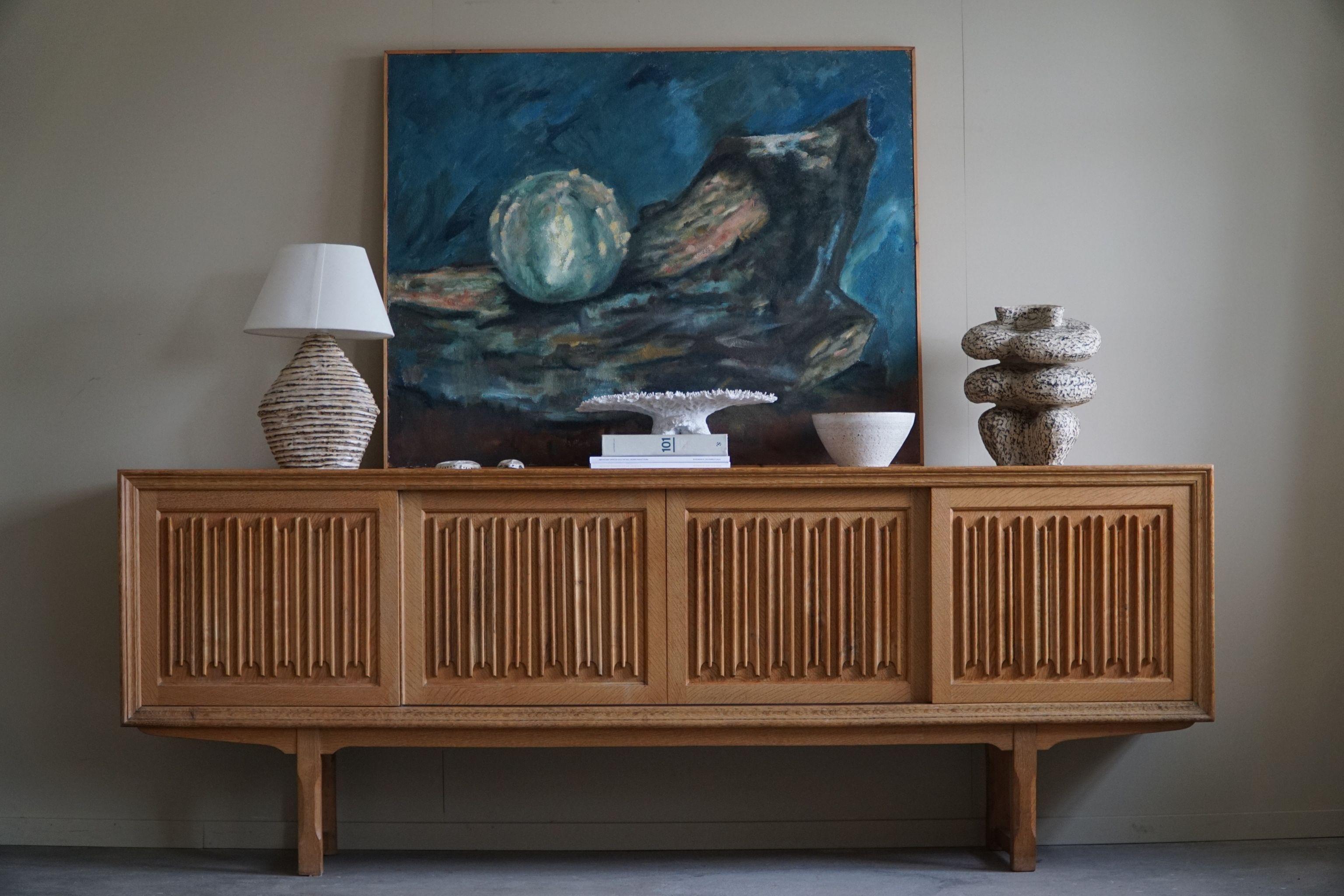 A sculptural low rectangular classic sideboard / cabinet in oak with plenty of storage and a beautiful carved front design. Made by a Danish cabinetmaker in the 1960s. 
Four sliding doors, inside storage and drawers.
This piece is in a good vintage