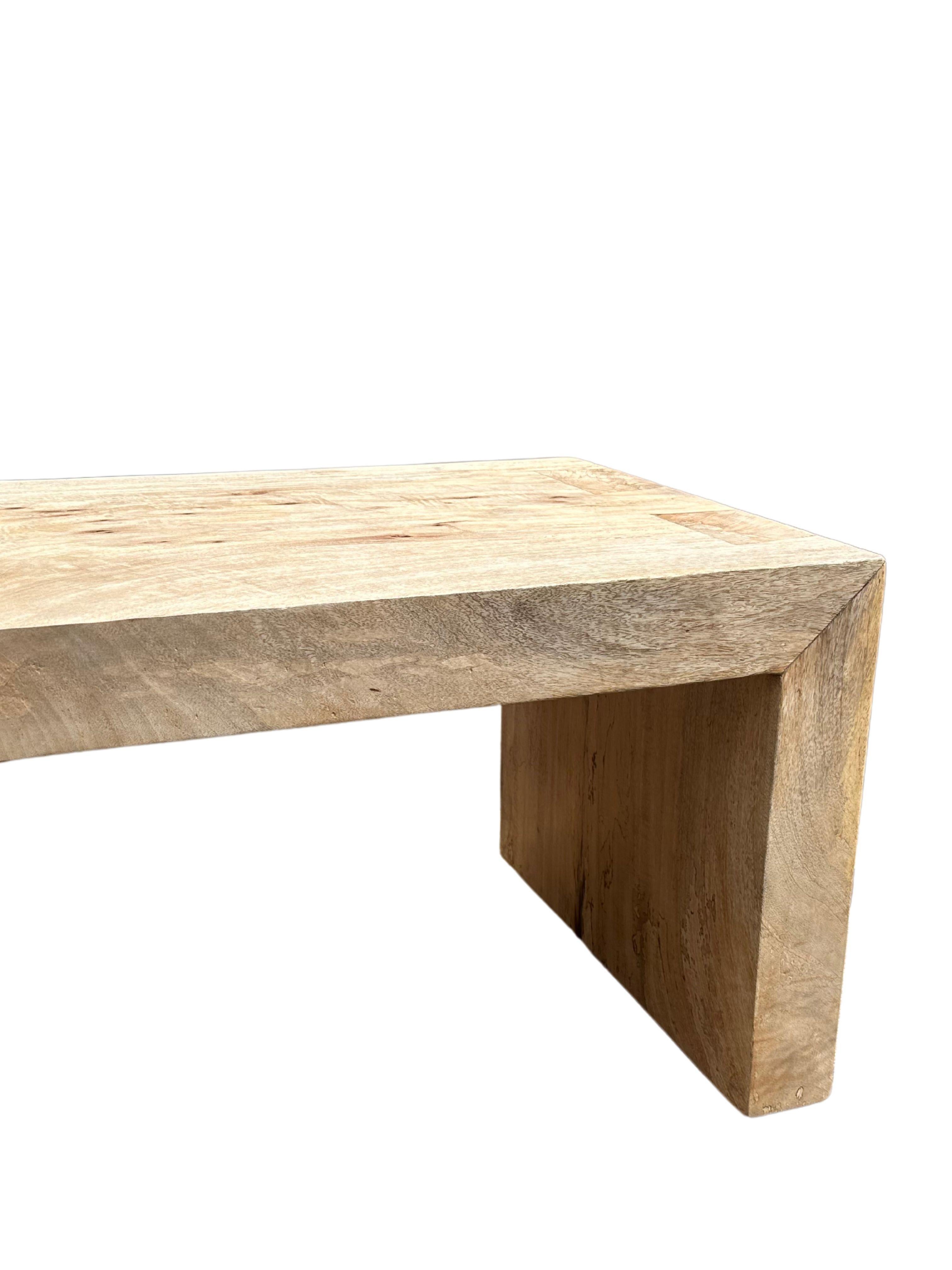 El banco se esculpió en madera maciza de mango. La madera utilizada para crear este banco es recuperada. Presenta un acabado natural con elegantes texturas y tonos de madera que le añaden encanto. El objeto perfecto para aportar calidez a cualquier