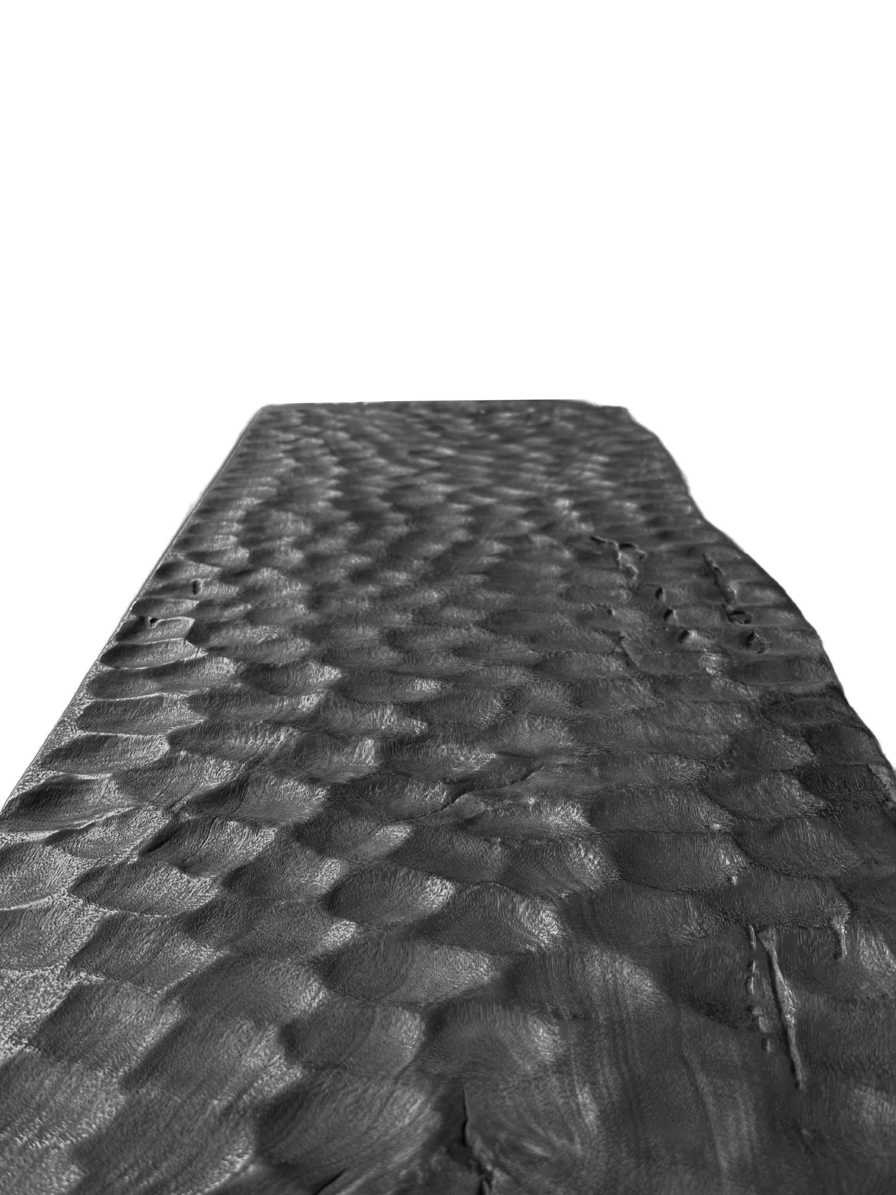 A sculptural hand-carved mango wood bench. To achieve is rich black pigment the bench was burnt three times and then finished with a clear coat. The mix of curved and straight lines along with a myriad of textures make for a very elegant bench.