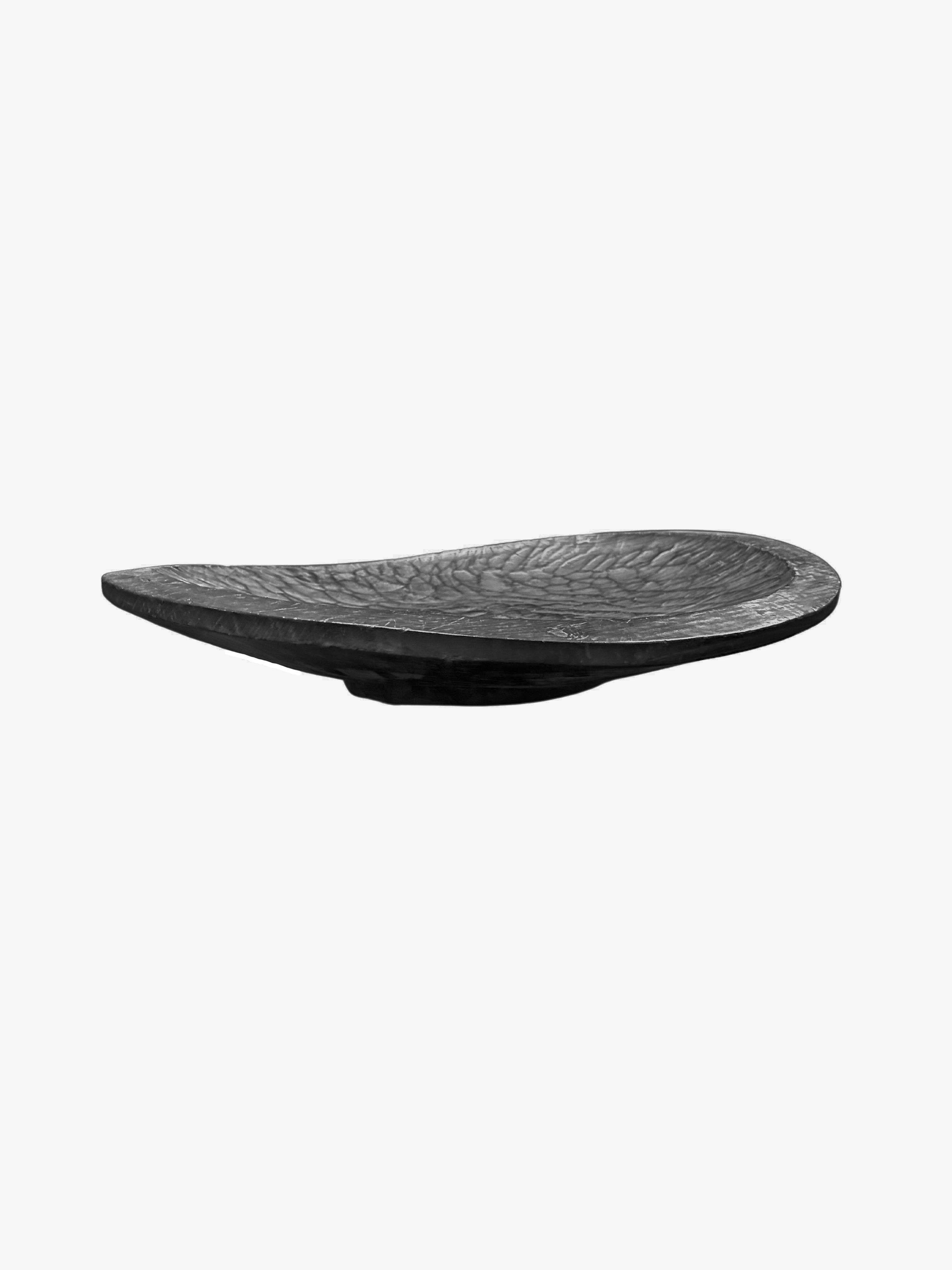 A hand-crafted mango wood bowl with hand-hewn detailing along the basin. The bowl was cut from a much larger slab of mango wood and features wonderful mix of wood textures. To achieve the rich black colour the bowl was burnt three times and finished