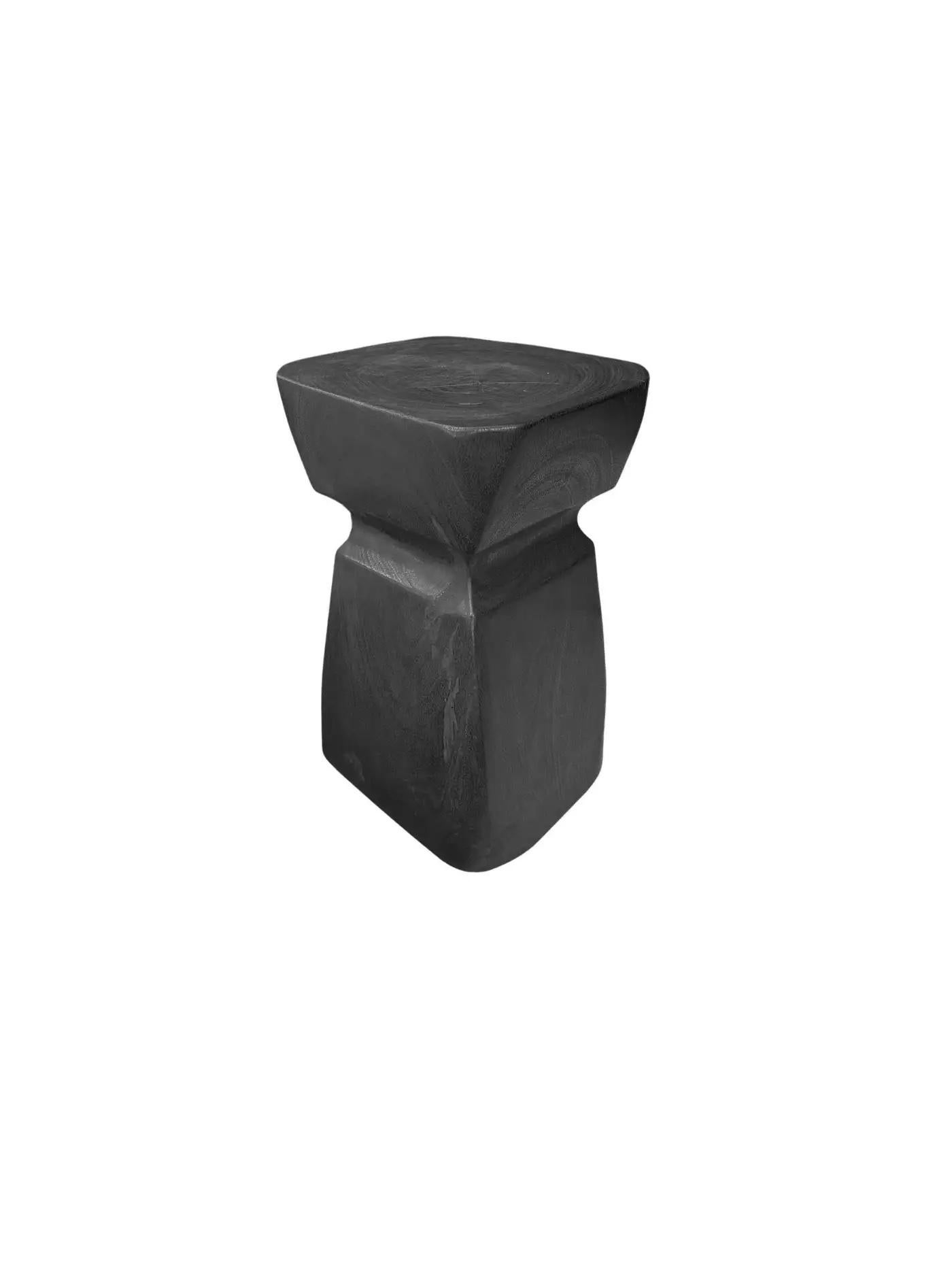Une table d'appoint merveilleusement sculptée, fabriquée à partir d'un seul bloc de bois de manguier. Il présente de merveilleuses textures de bois. Pour obtenir sa finition noire, le bois a été brûlé plusieurs fois et recouvert d'une couche