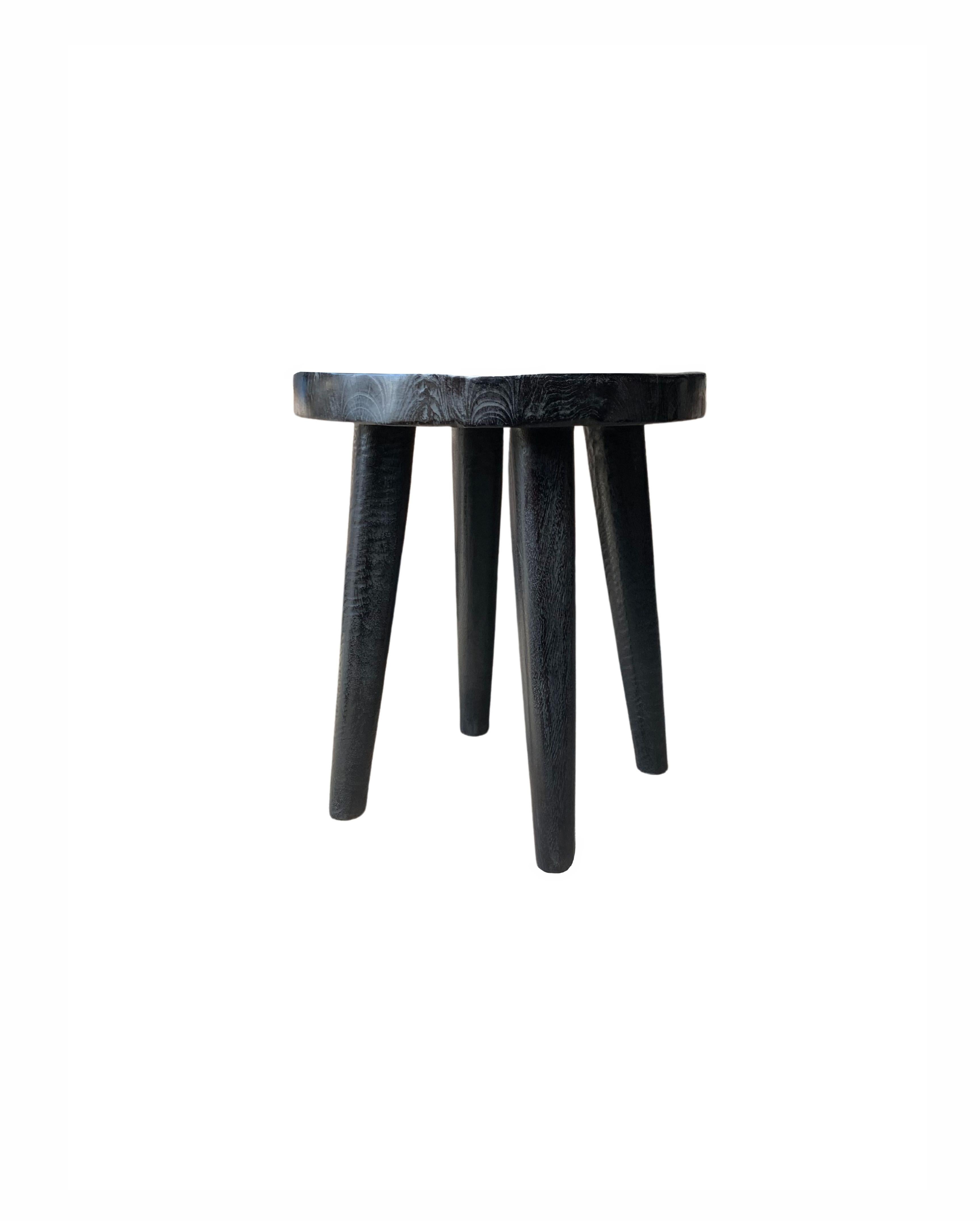A sculptural mango wood stool with a mix of textures and shades. This stool features wonderful elongated and slender legs. The legs have been sanded down meticulously to create a smooth texture and contrast in colour and textures to the seat. The