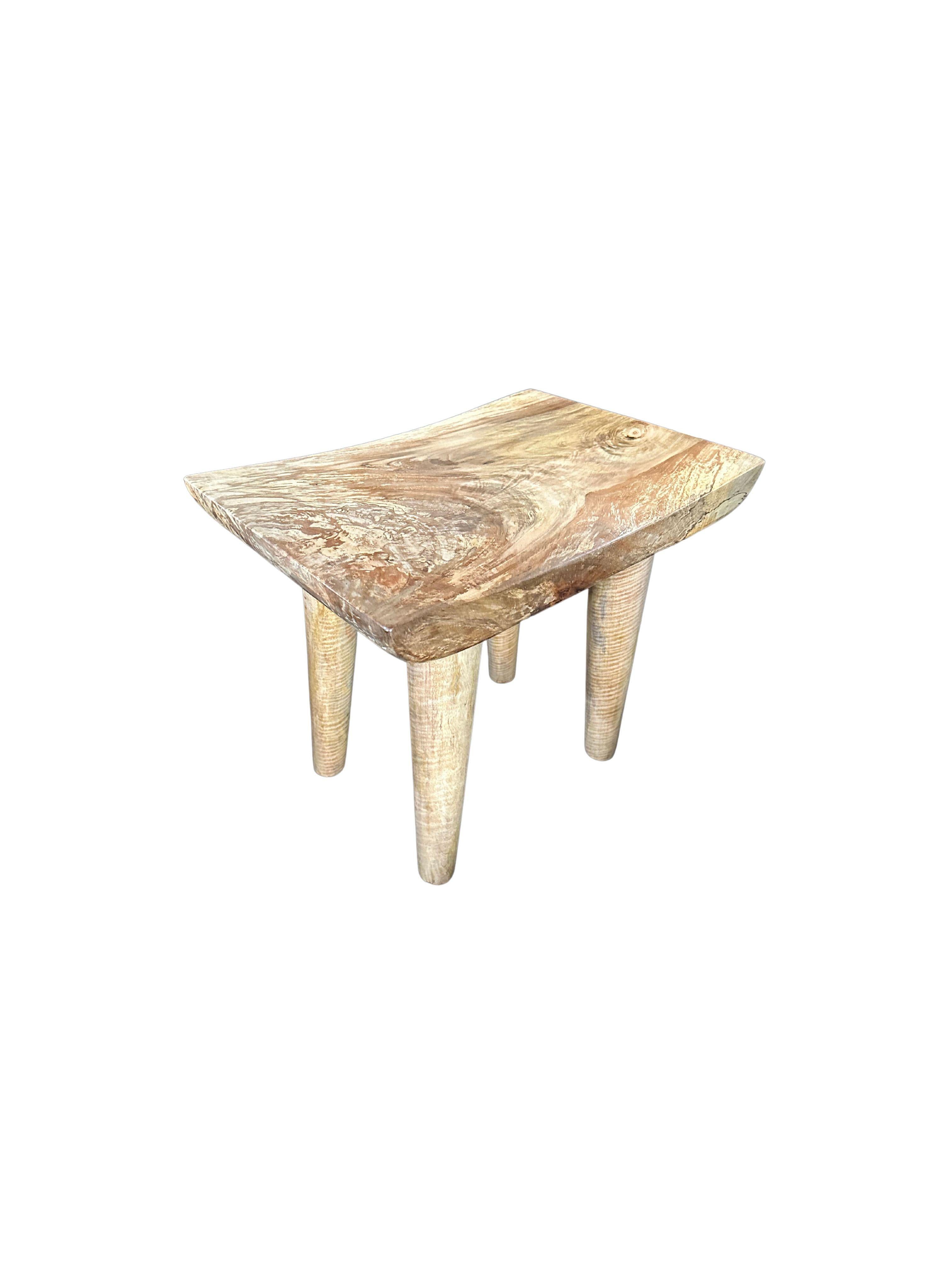 A wonderfully sculptural stool with a curved seat. The stool's neutral pigment and subtle wood texture makes it perfect for any space. A uniquely sculptural and versatile piece. This stool was crafted from solid mango wood.

