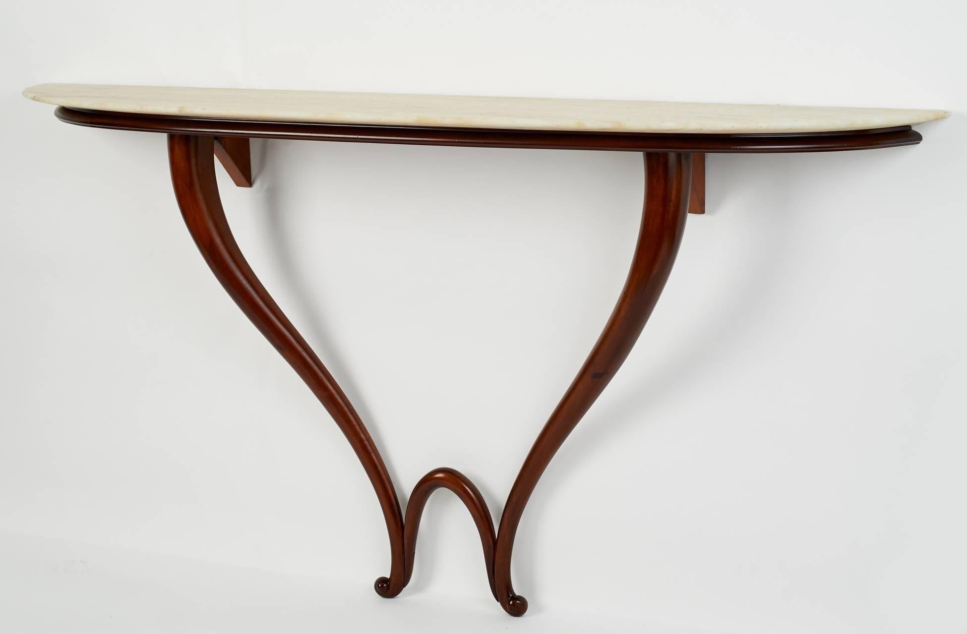 A sculptural double-beveled mahogany console in the style of Gio Ponti, with a delicately curving and tapered base supporting a graciously shaped razor-edge marble top.