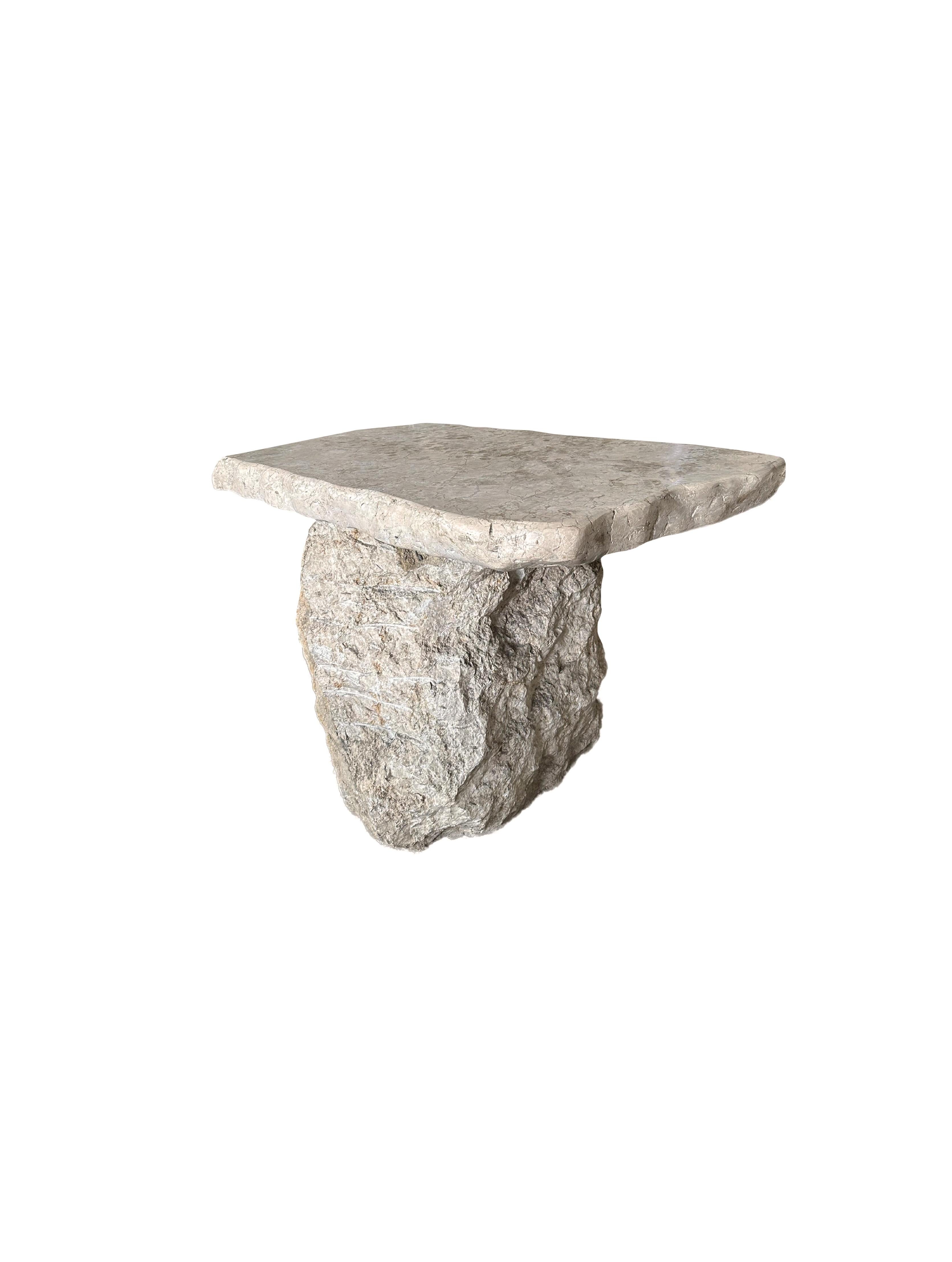 A sculptural marble table, featuring a wonderful mixture of textures and shades. This table features a rough textured, solid base and a solid table top that has been polished. The mix of curved and straight lines adds to its charm.