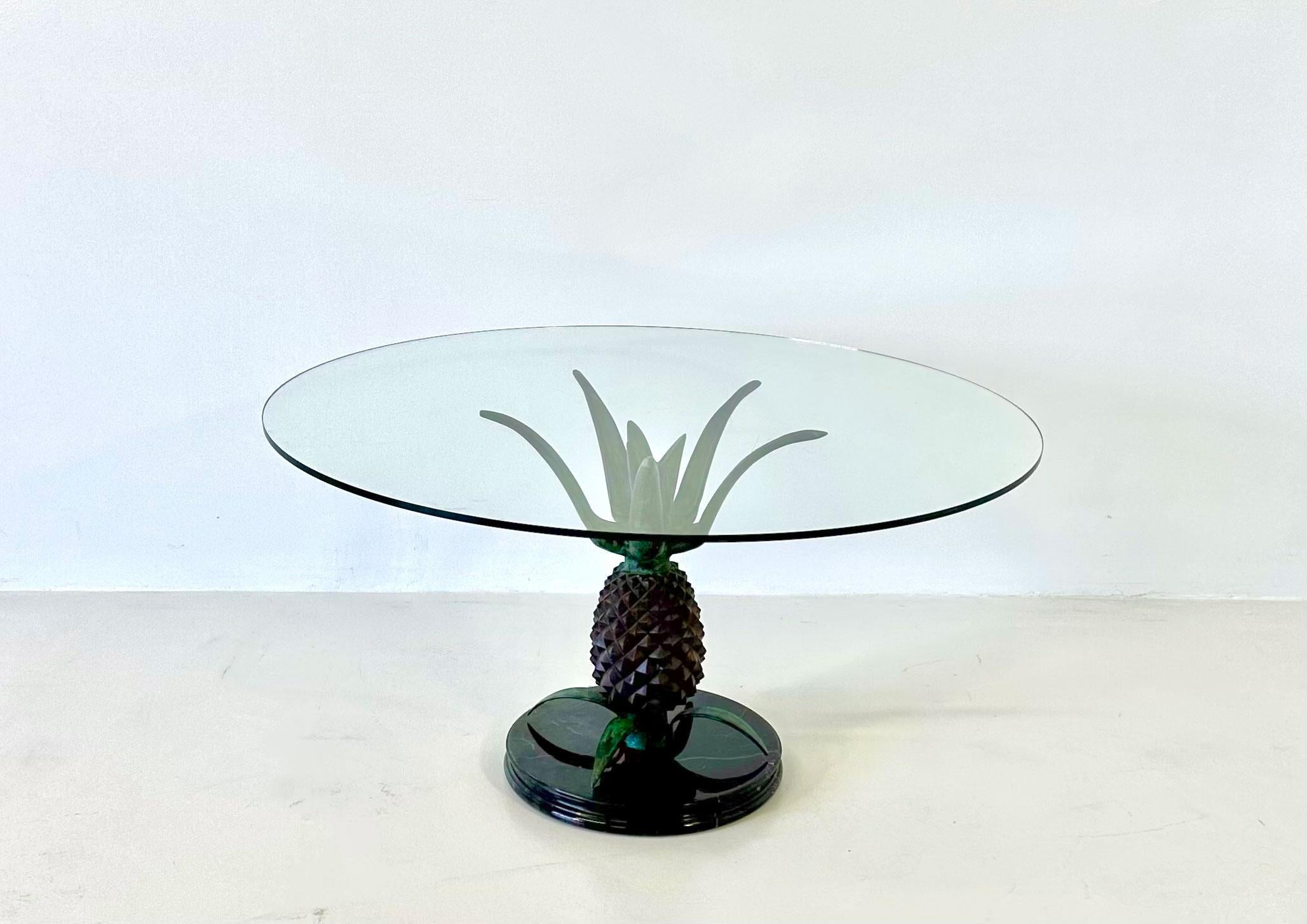 This unusual and one of a kind coffee table was produced in France in the 1970s and it is attributable to the Maison Jansen. 
The coffee table features a pineapple shaped metal leg on an elegant black marble base and a glass top. 
In very good