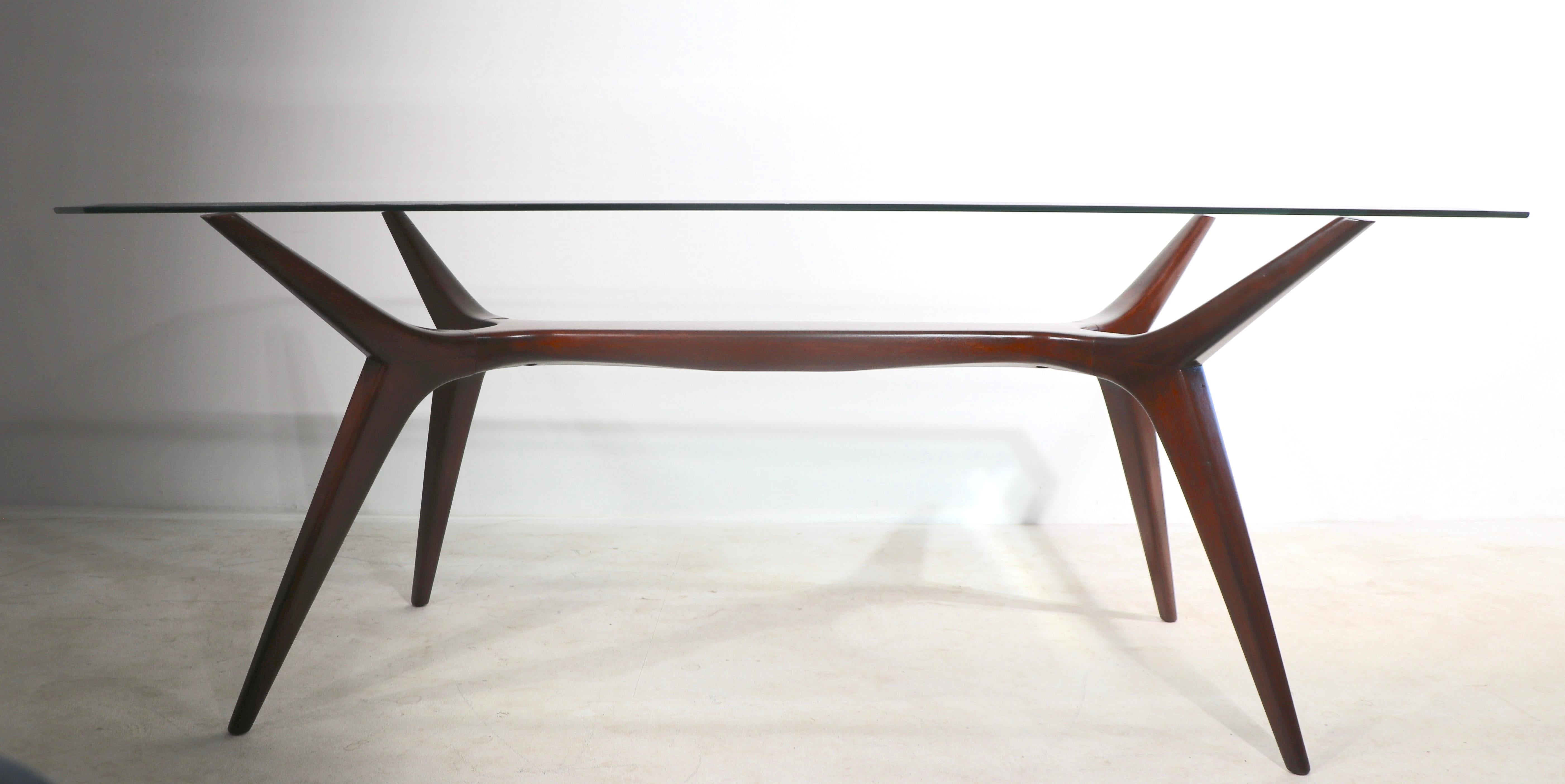 Rare sculptural dining table of cuban mahogany, and plate glass. The base is of solid Cuba mahogany, with a bevelled plate glass top. The wood base has been professionally refinished, the glass top is free of damage, but we are not convinced its is
