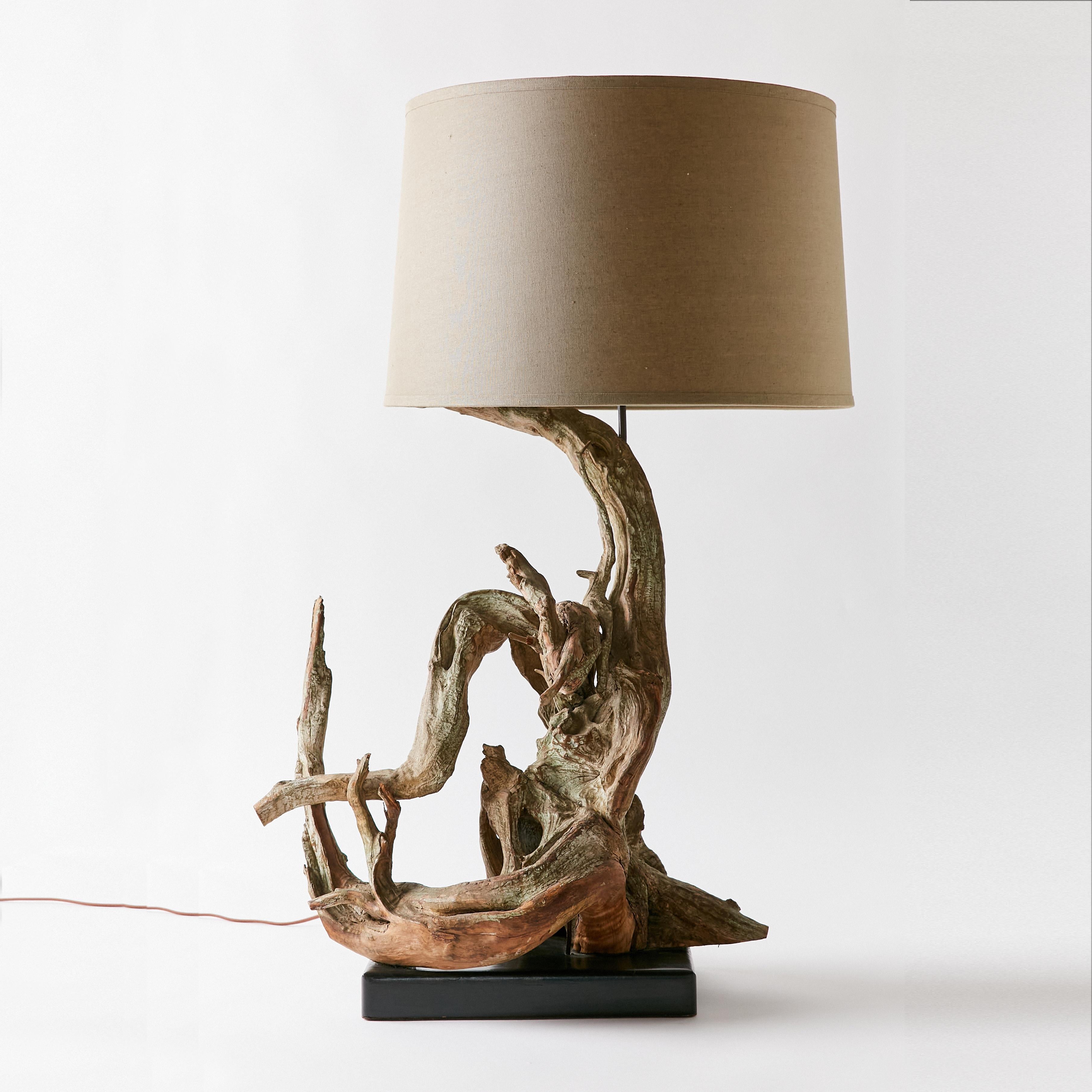 Sculptural mid-century driftwood lamp with wooden base. It shows a well-worn natural patina. This item has been rewired with new braided cloth cord and hardware. This lamp does not include shade or harp.