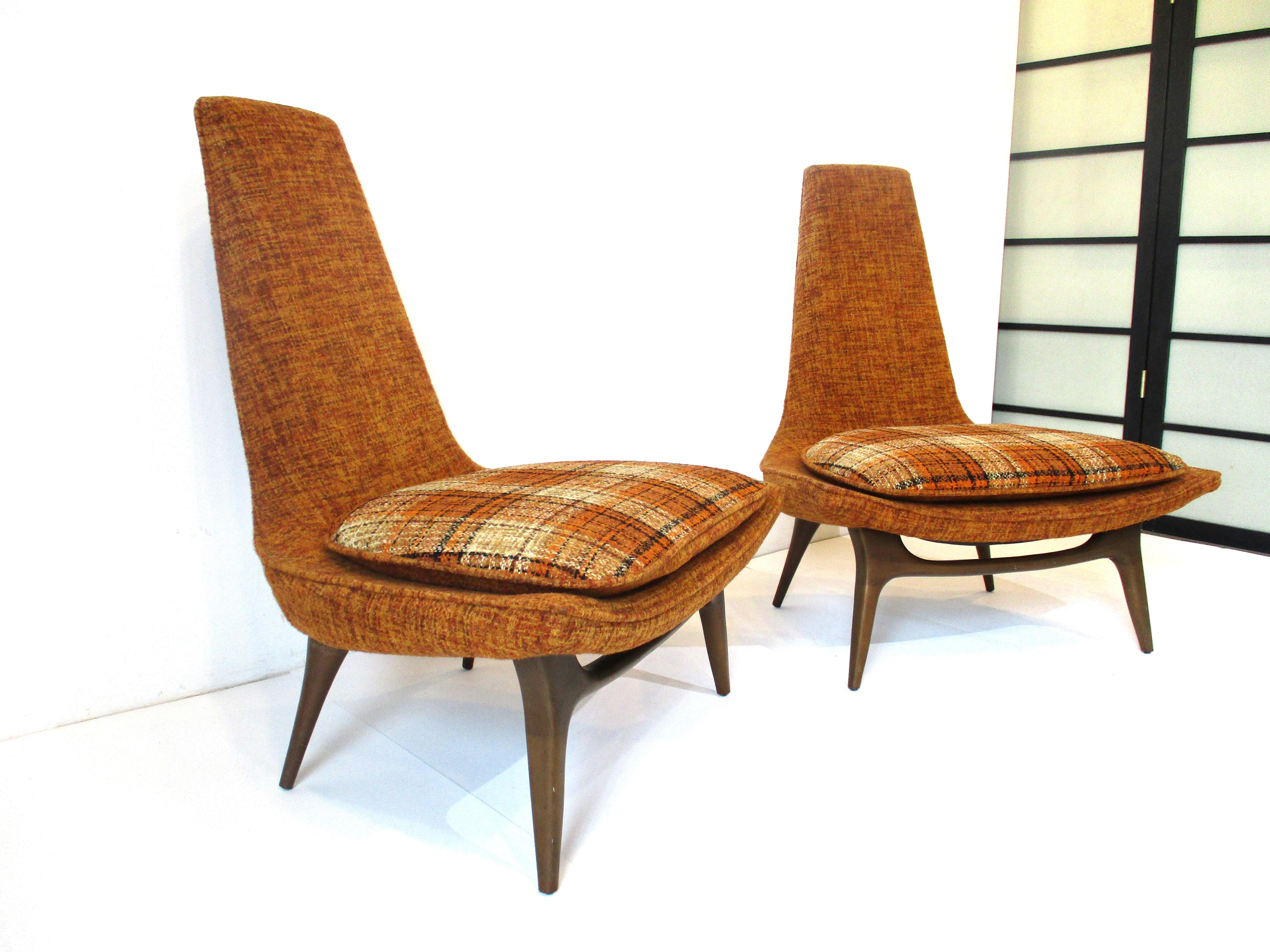 A very sculptural pair of midcentury Slipper lounge chairs in the original fabric which is in super condition. The legs are in a dark toned wood having a wide loose bottom cushion and high back for comfort. These chairs will make a statement in any