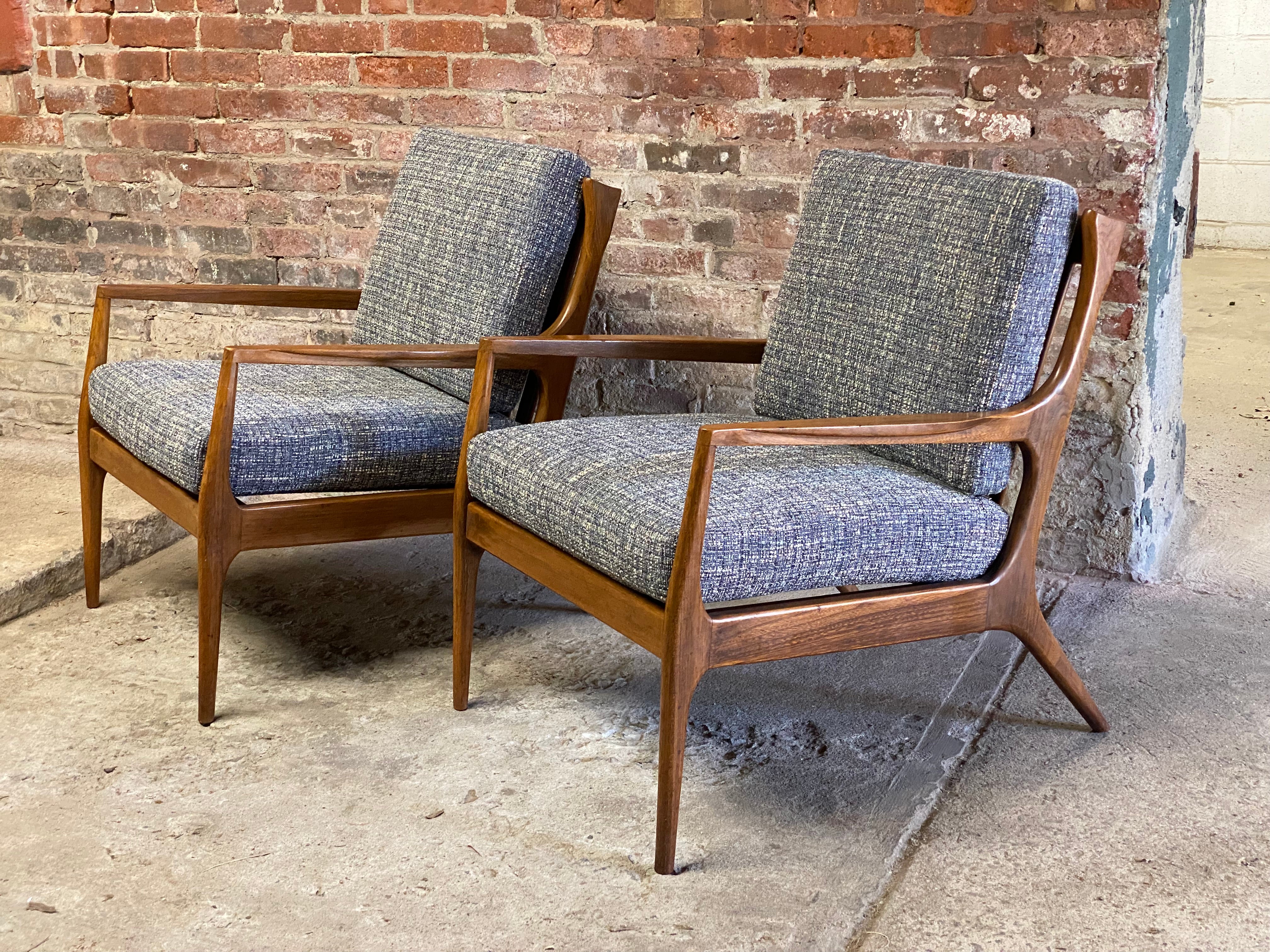 A very fine pair of sculptural frame walnut finish lounge armchairs. This pair features a modern twist wing back flared side detail, an amazing profile, finely tapered legs, slat backs and contoured arm rests. Circa 1960. Freshly upholstered with