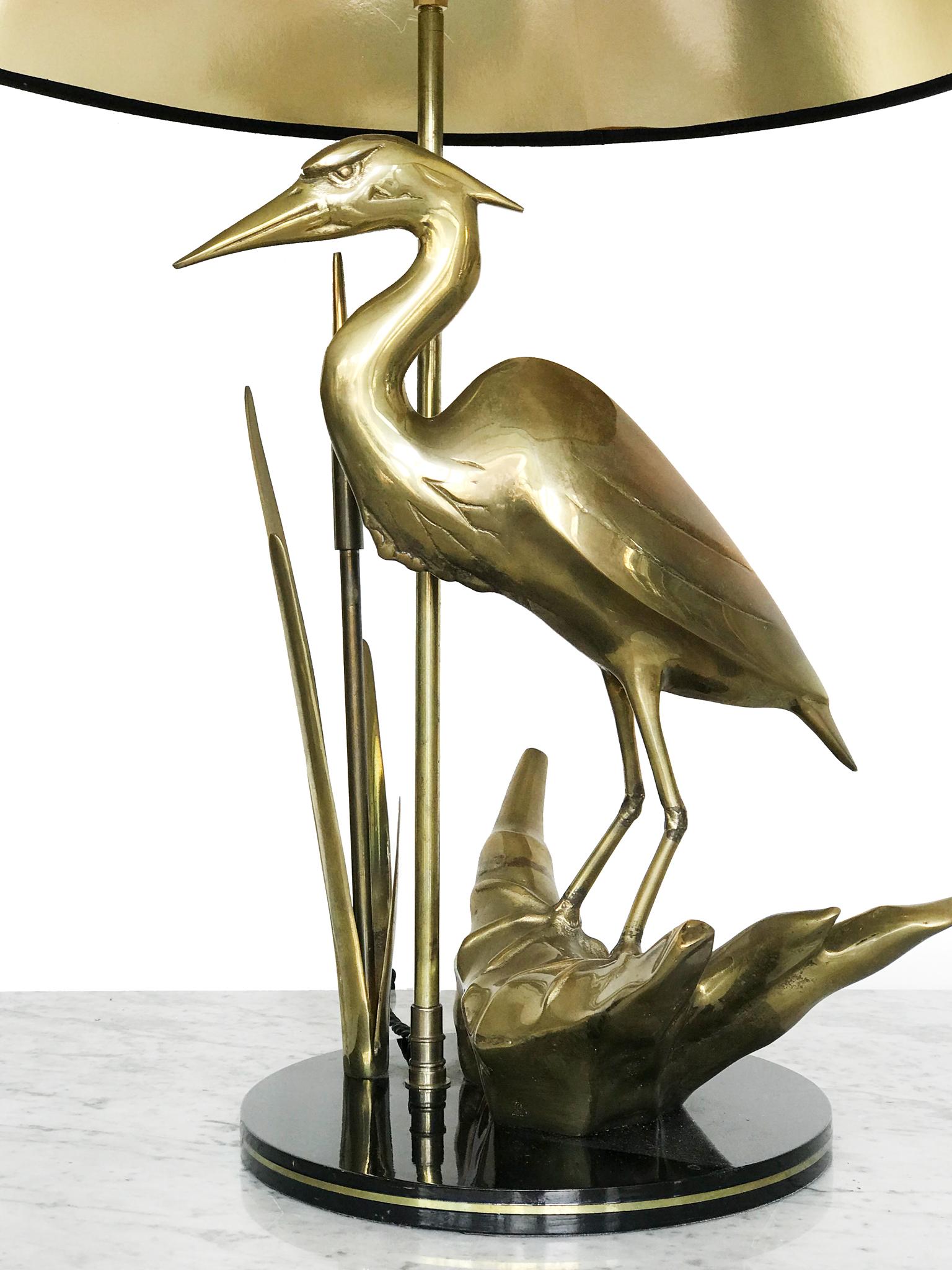 A sculptural lamp in brass formed as a heron in a naturalistic setting with reed detail. Set on a circular black gloss base. Original black shade with gold lining. 
This stylish French lamp has a luxurious appeal.
Height including: 74cm
Height