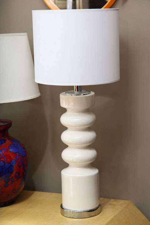 A white ceramic table lamp with chrome base and hardware. USA, circa 1960. Rewired for USA; takes one standard bulb, 75 watts max. White paper drum shade is included.

Dimensions:
Height of ceramic base only 15 inches
Height to socket 17.25