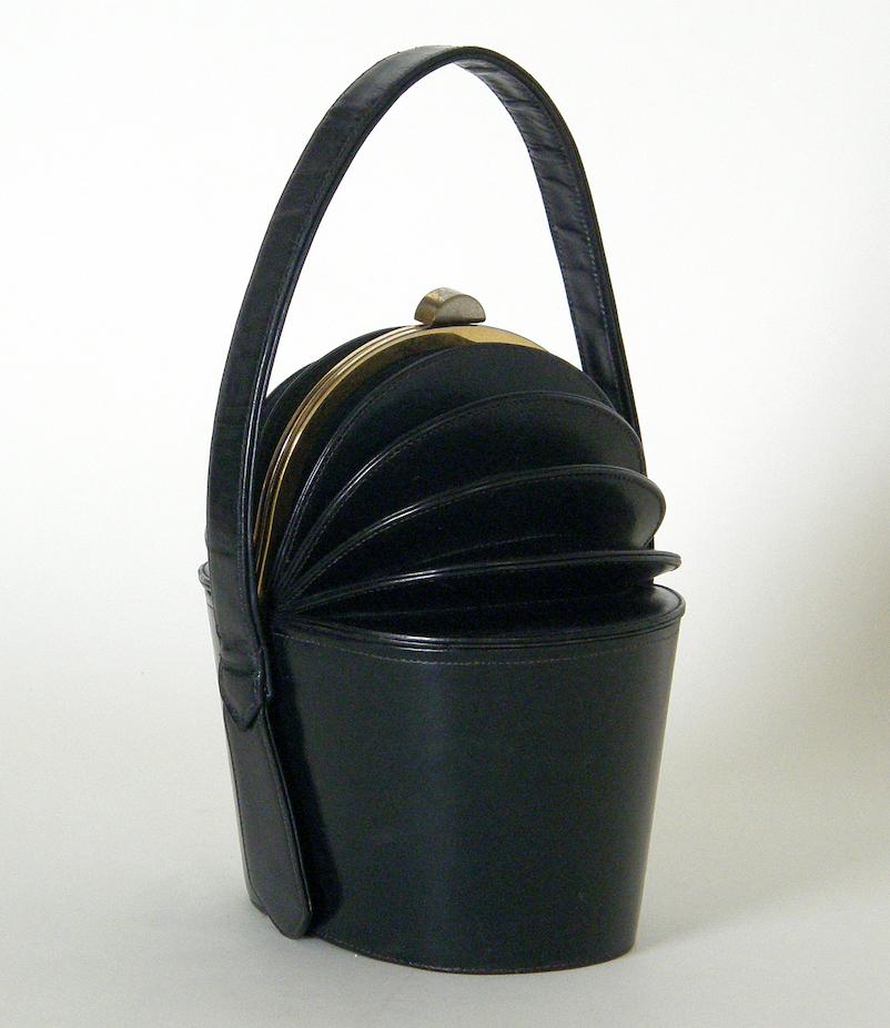 Wonderfully engineered box bag with an accordion shaped top by Eli Bogan. This cleverly designed handbag is very modern, though it was patented in 1949. The bag is made of midnight blue leather. The folded top opens to a roomy interior.

measures 8