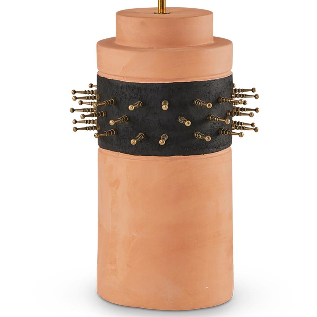 Hand-molded terracotta forms the base of this lamp, stripe detail finished with black plaster and adorned with bronzed steel spikes. It's a bold statement piece that channels a rebellious spirit.