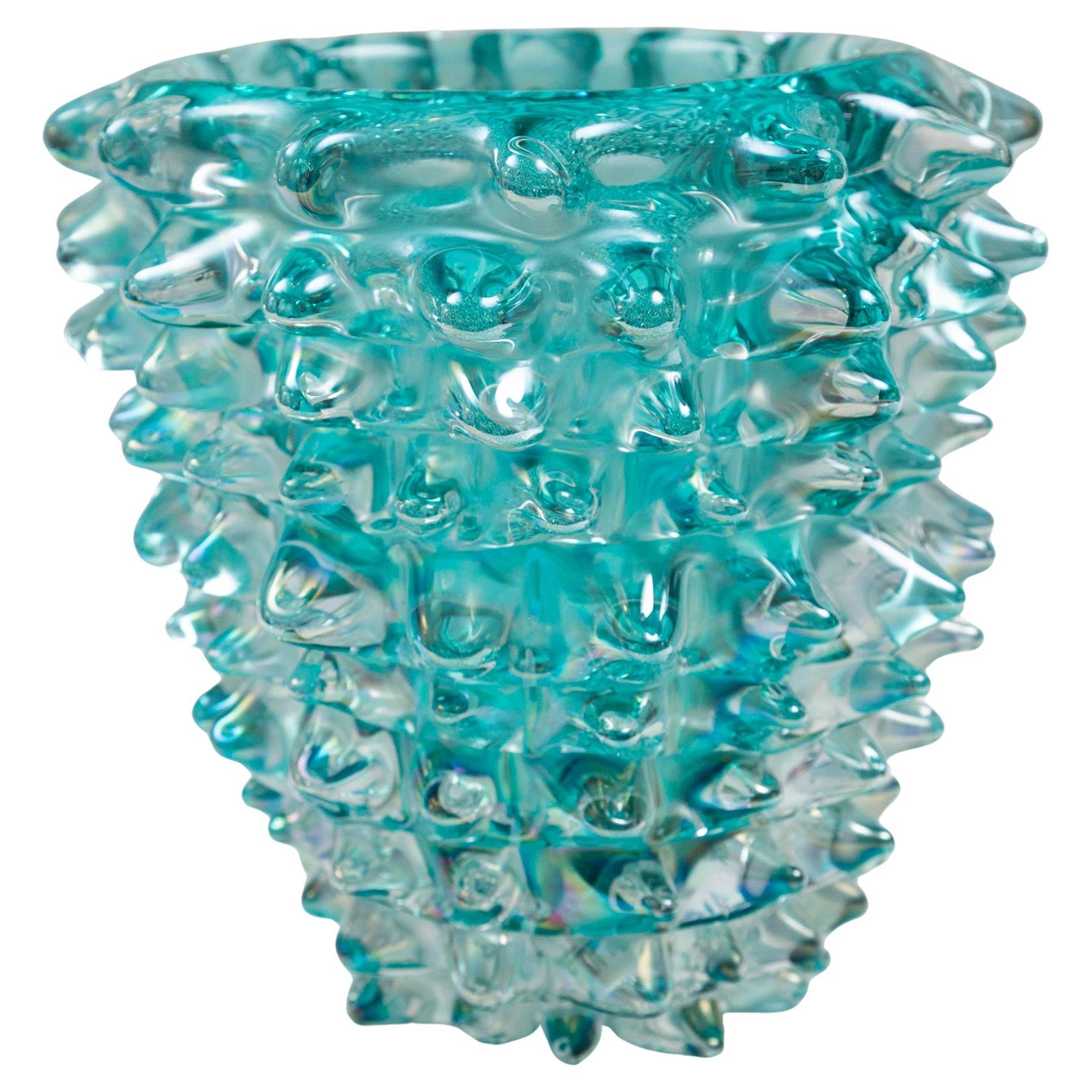 Eine erhabene, mundgeblasene Vase in schillerndem Aquamarin. Das in das Glas geblasene Schillern verleiht dieser schönen Farbe eine zusätzliche Dimension, einen Effekt der Bewegung, wenn sich das Licht um sie herum verändert.    Jede Spitze wird von