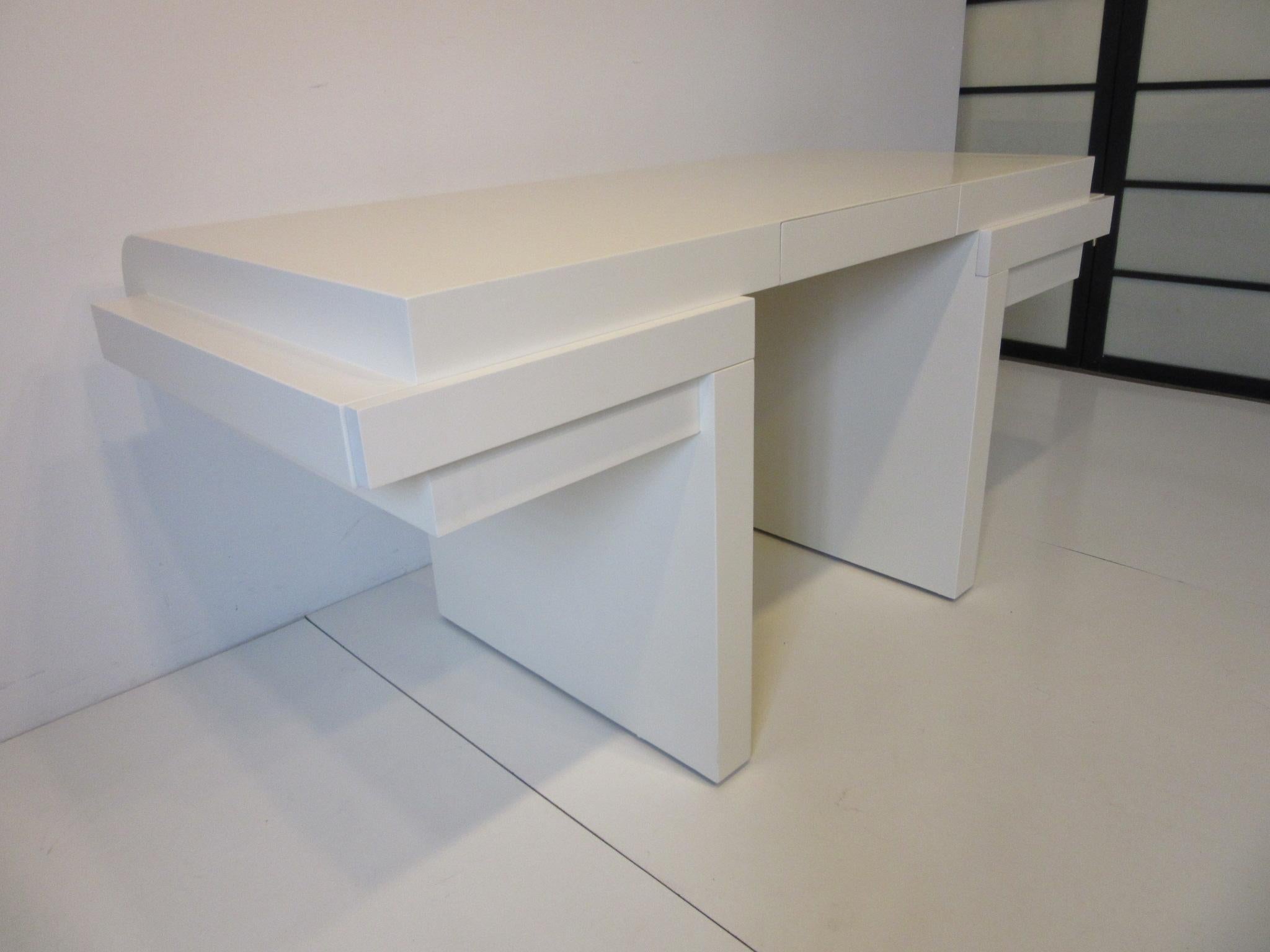 A light cream colored sculptural wood desk with pedestal base, rounded front and to the other side three small drawers. This desk makes a subtle simple statement but has a lot of design power making this the perfect piece for home or office, a well