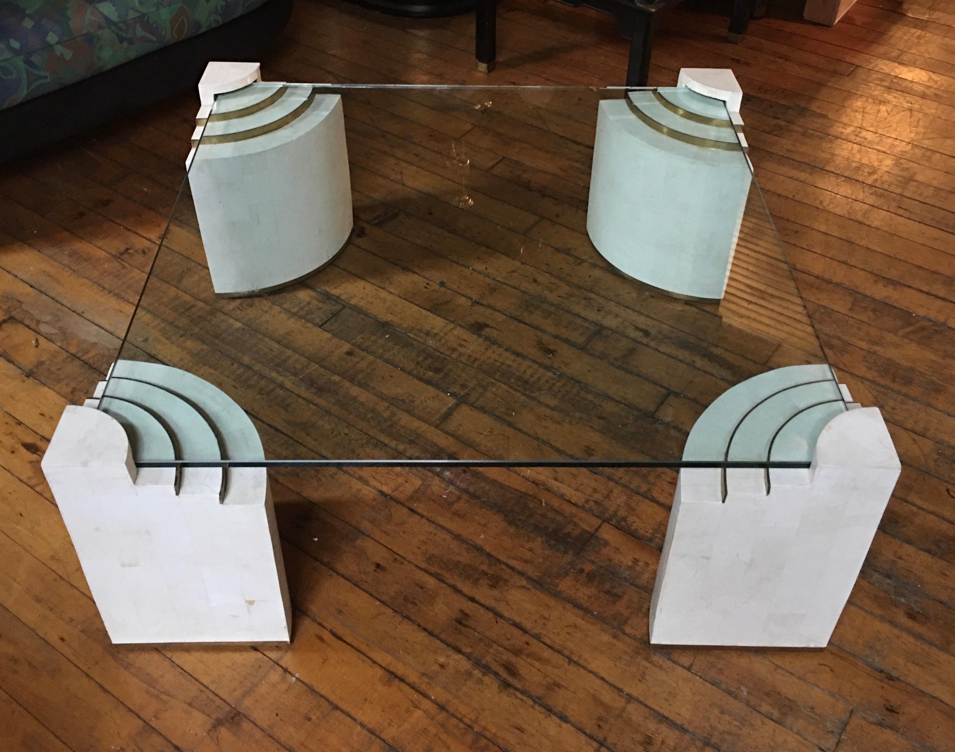 Stunning Mid-Century Modern tessellated stone coffee table designed by Robert Marcius for Casa Bique. Large square glass top is supported by four sculptural tessellated stone legs with brass band/trim detailing. In the style of Maitland Smith and in