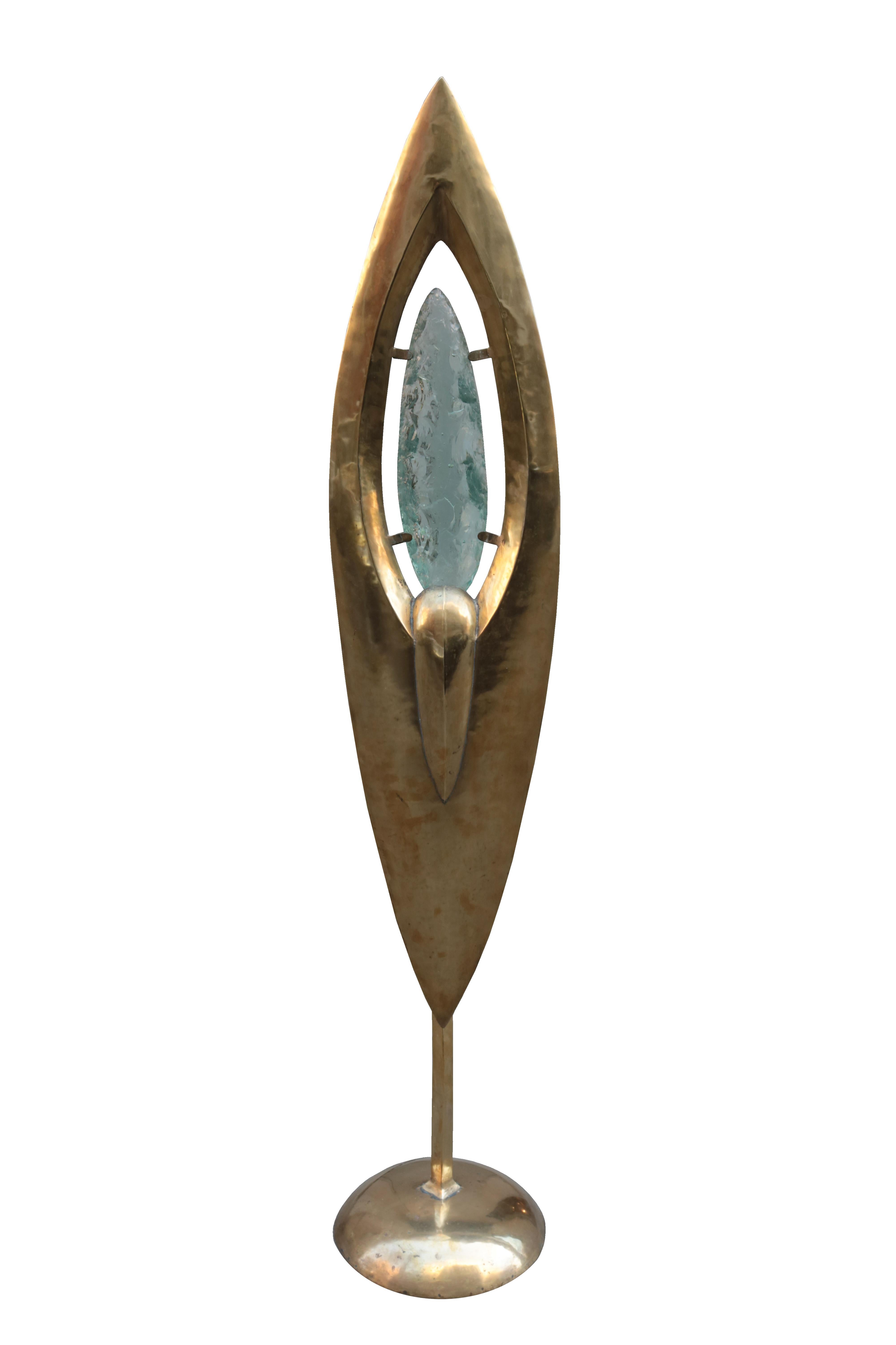 Unusual sculptural Modernist floor lamp. 
Patinated brass with an illuminated piece of rough cut glass 
mounted in the center. Glass has blue hue when illuminated.