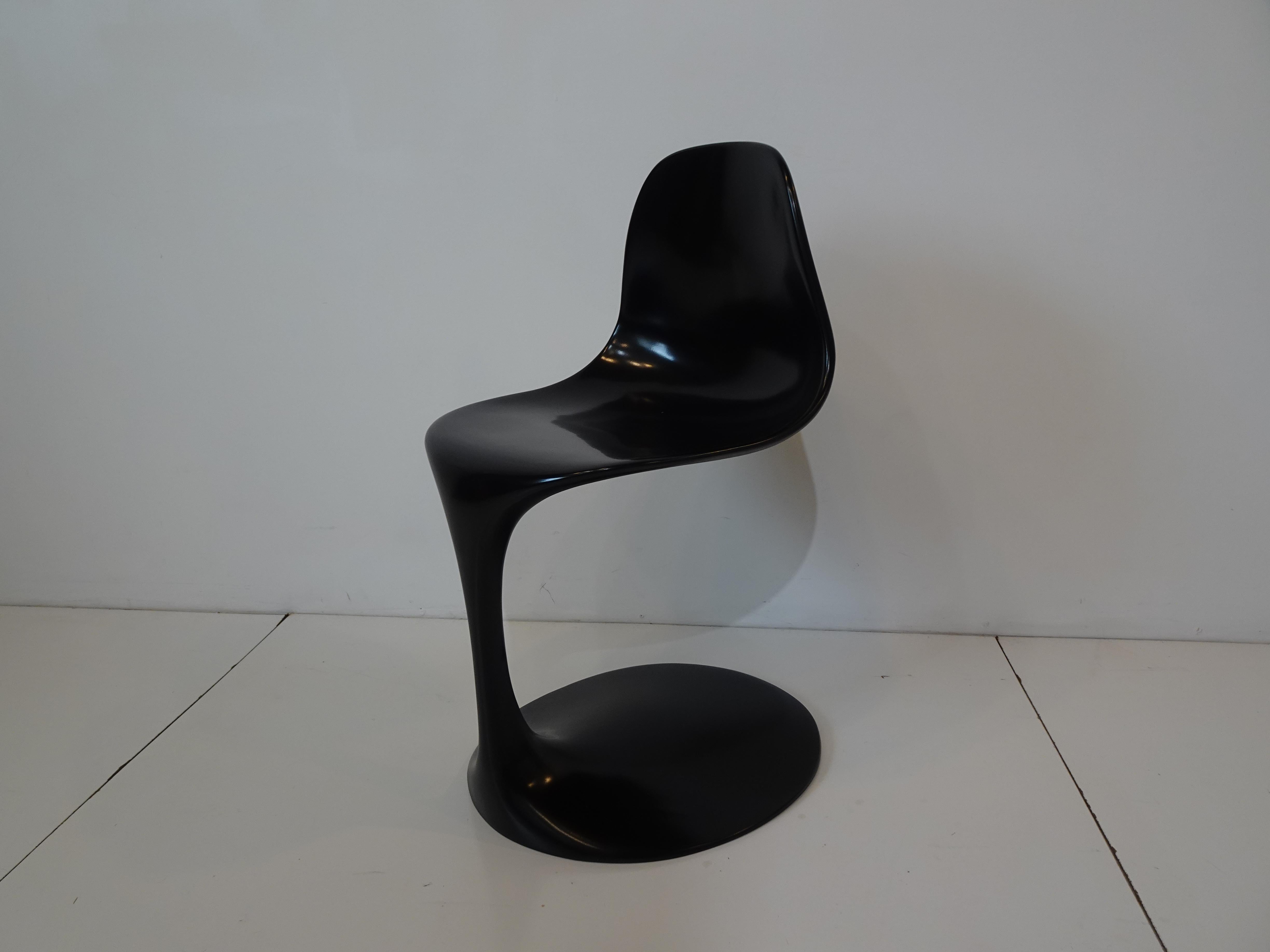Una sedia scultorea in fibra di vetro stampata nera, disegnata da Rudi Bonzanini, che poggia su uno stelo molto sottile che va dalla seduta alla base ovale. Un'opera d'arte che è una sedia che sembra uscita da una lattina, mantenendo le informazioni