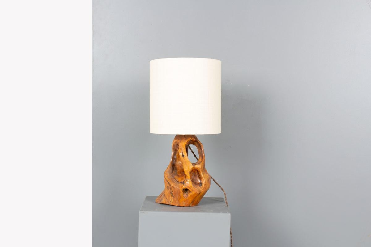 Crafted in France during the 1950s, this unique table lamp is a stunning example of organic design. Its base is carved from solid olive wood, revealing expressive natural grain patterns and a free-form silhouette that gives the piece a sculptural