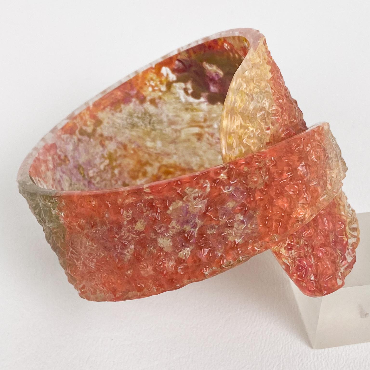 Ce bracelet sculptural en Lucite ou en Plexiglas, réalisé par un studio de design italien, présente une forme asymétrique impressionnante avec un design enroulé et un motif texturé ridé ou glacé, complété par une application de peinture en aérosol