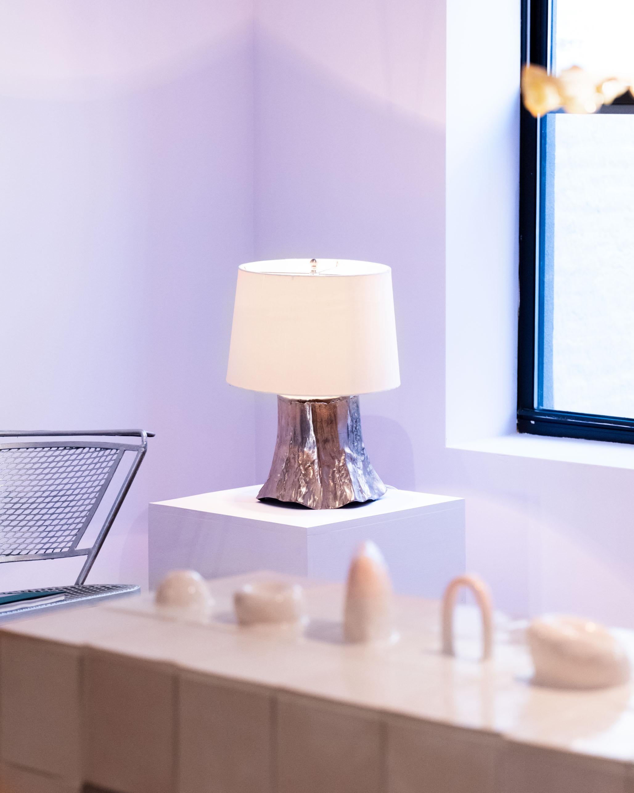 A striking vintage table lamp featuring a sculptural cast metal base that mimics the organic texture of a tree trunk. The raw, molten-like finish adds a Brutalist edge, while the neutral linen shade softens the silhouette with a touch of warmth. A
