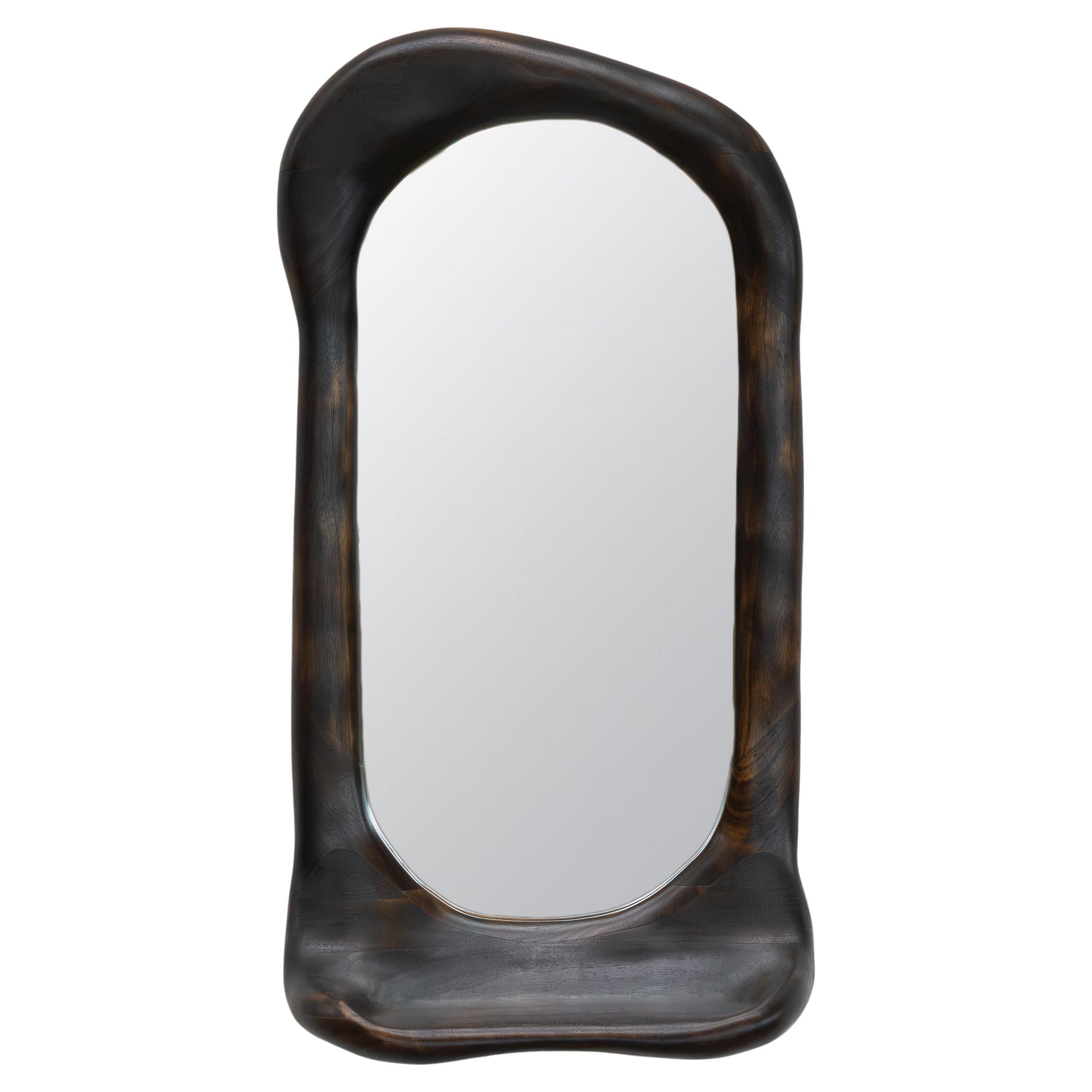 Le cadre du miroir est façonné à l'aide de divers outils manuels, ce qui rend chaque pièce unique avec son propre grain de bois distinctif. Le miroir est fabriqué en noyer de haute qualité, légèrement brûlé et recouvert d'une huile à base de cire