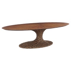 Mesa de comedor ovalada de diseño escultural de Albino Miranda, con tablero de nogal y base de fundición