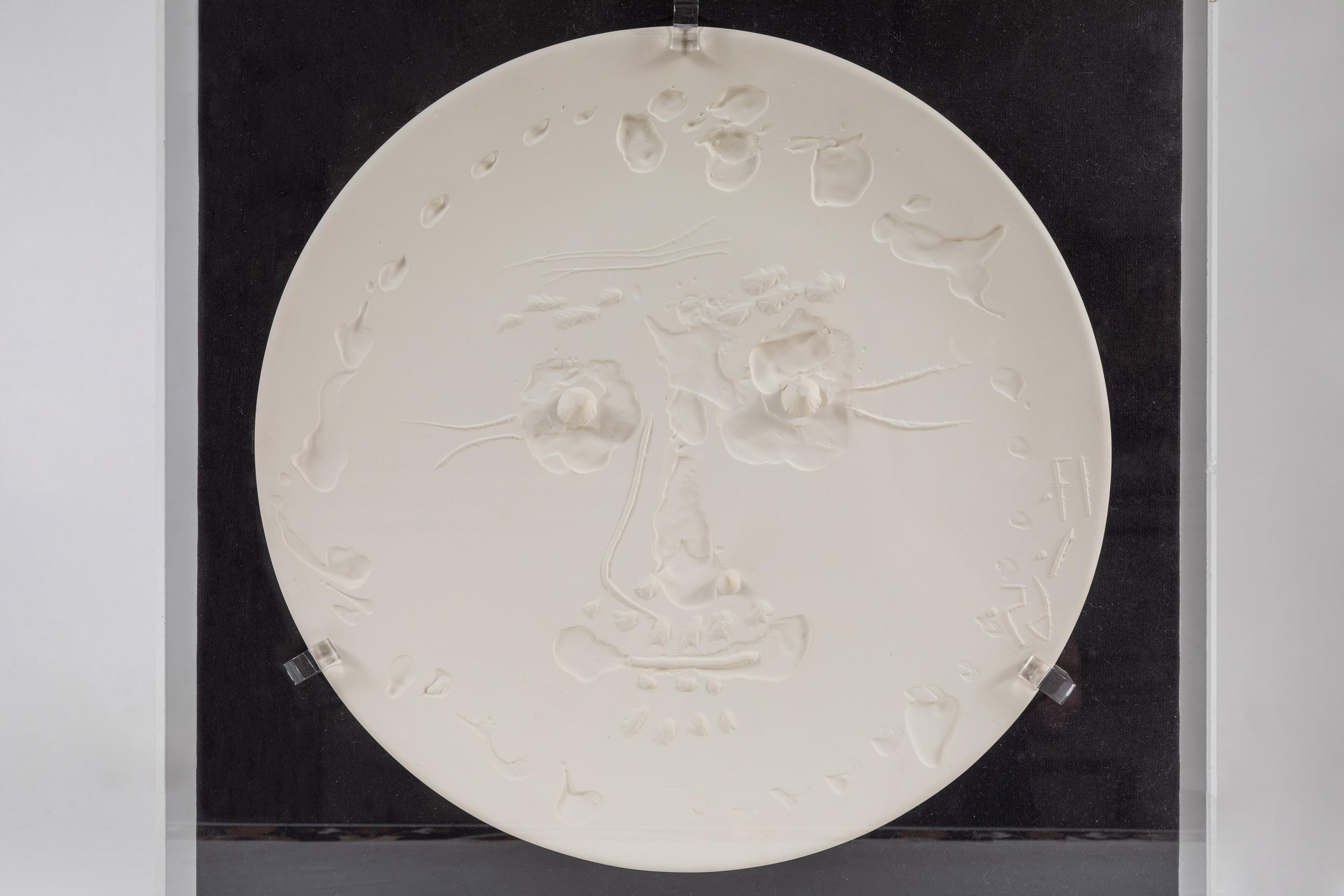 Signed and stamped, large, unglazed light ceramic earthenware plate with raised design from the “Tormented Face” series by Pablo Picassso (1881-1973). Procuced by the Madoura Foundry, France in 1956. Held in a custom, Lucite frame with black velvet