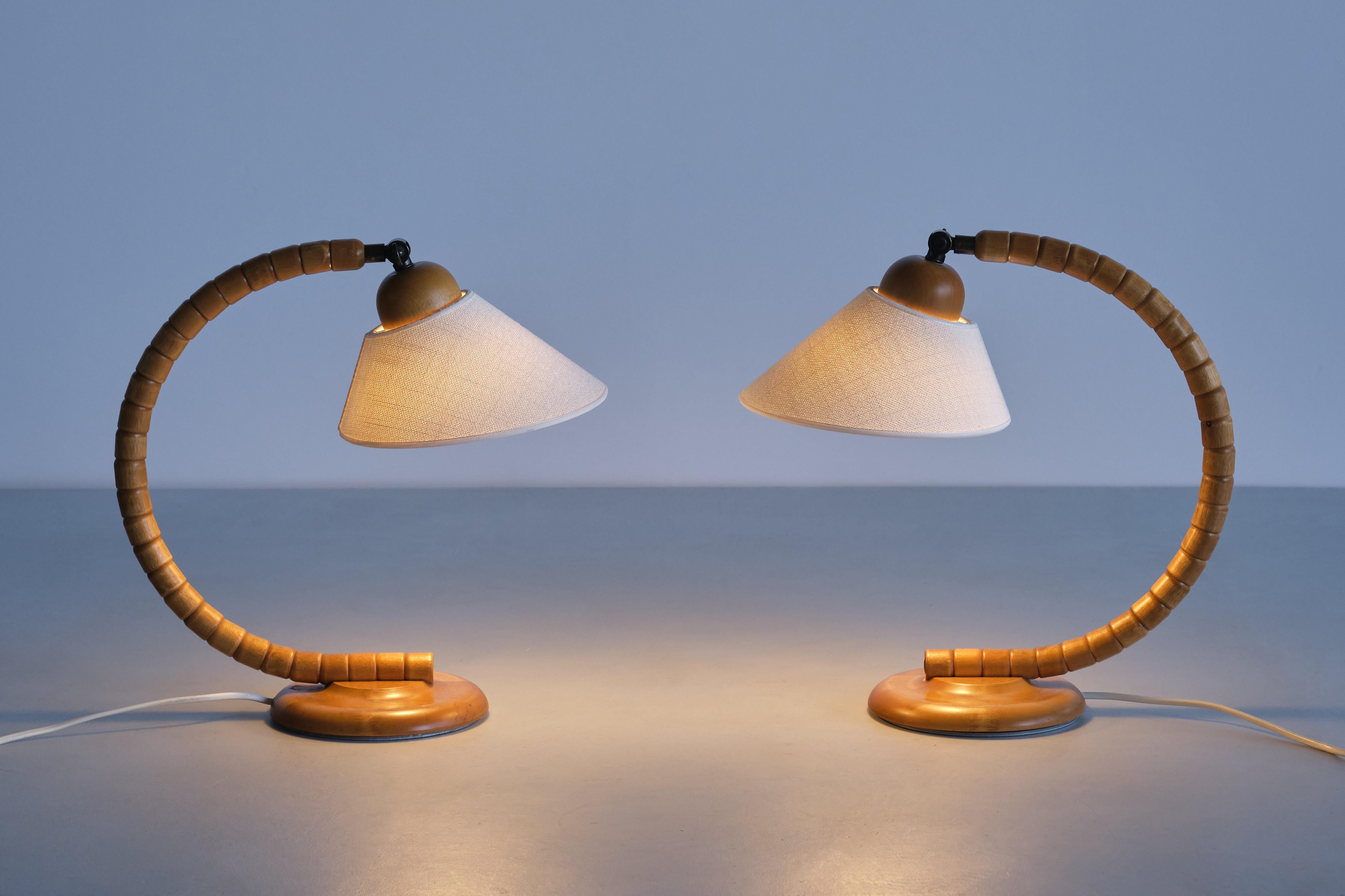 This striking pair of table lamps was produced by Markslöjd in Kinna, Sweden in the 1960s. The design is marked by the sculptural, organic shaped frame resting on a circular base. The base is made of solid stained beech wood. Brass fittings, and