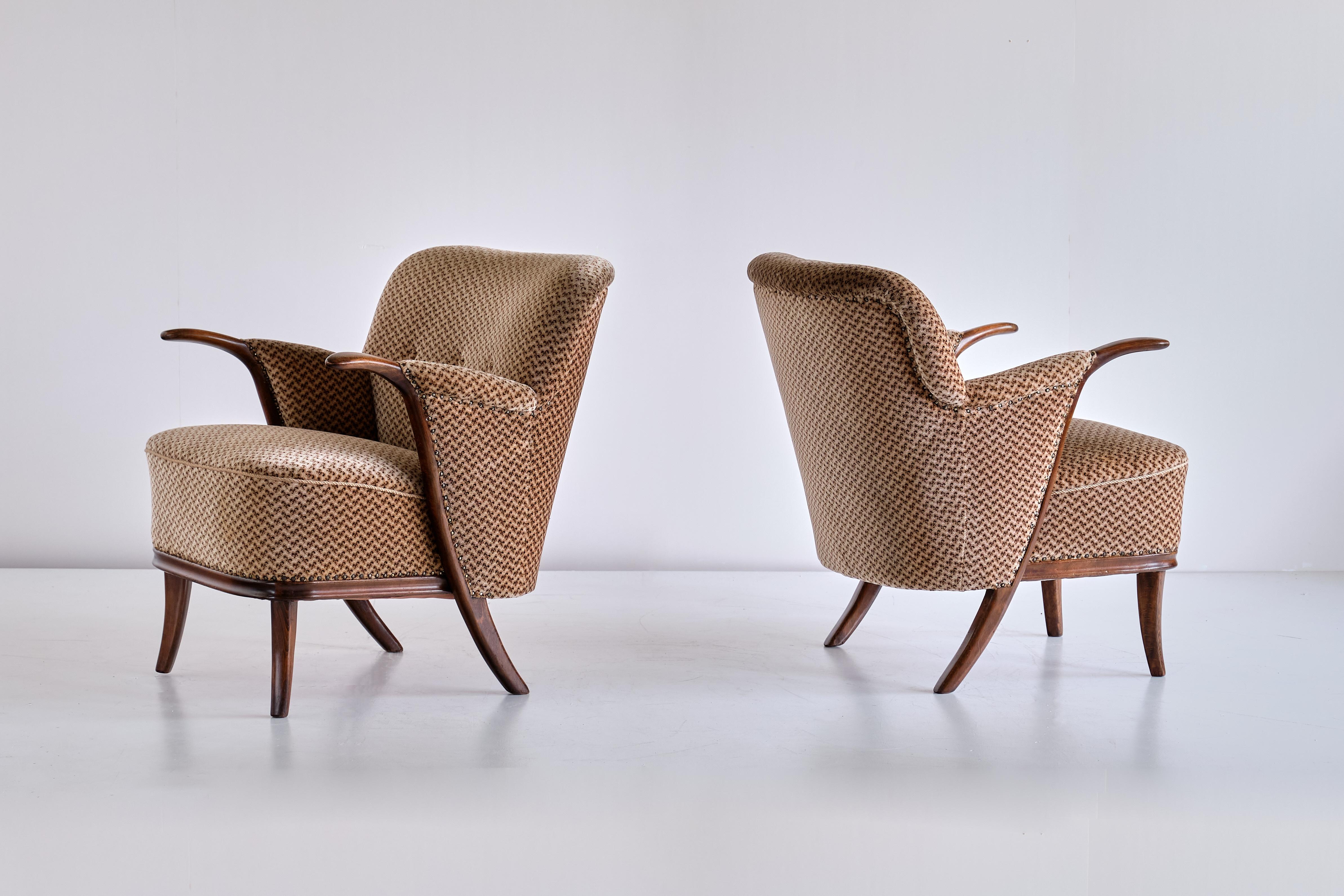 Cette paire de fauteuils rares a été conçue par Adolf Wrenger et produite par sa société à Lippe, en Allemagne, au début des années 1950. Les cadres sont en hêtre massif teinté, avec des accoudoirs sculpturaux reliés par une ligne courbe aux pieds