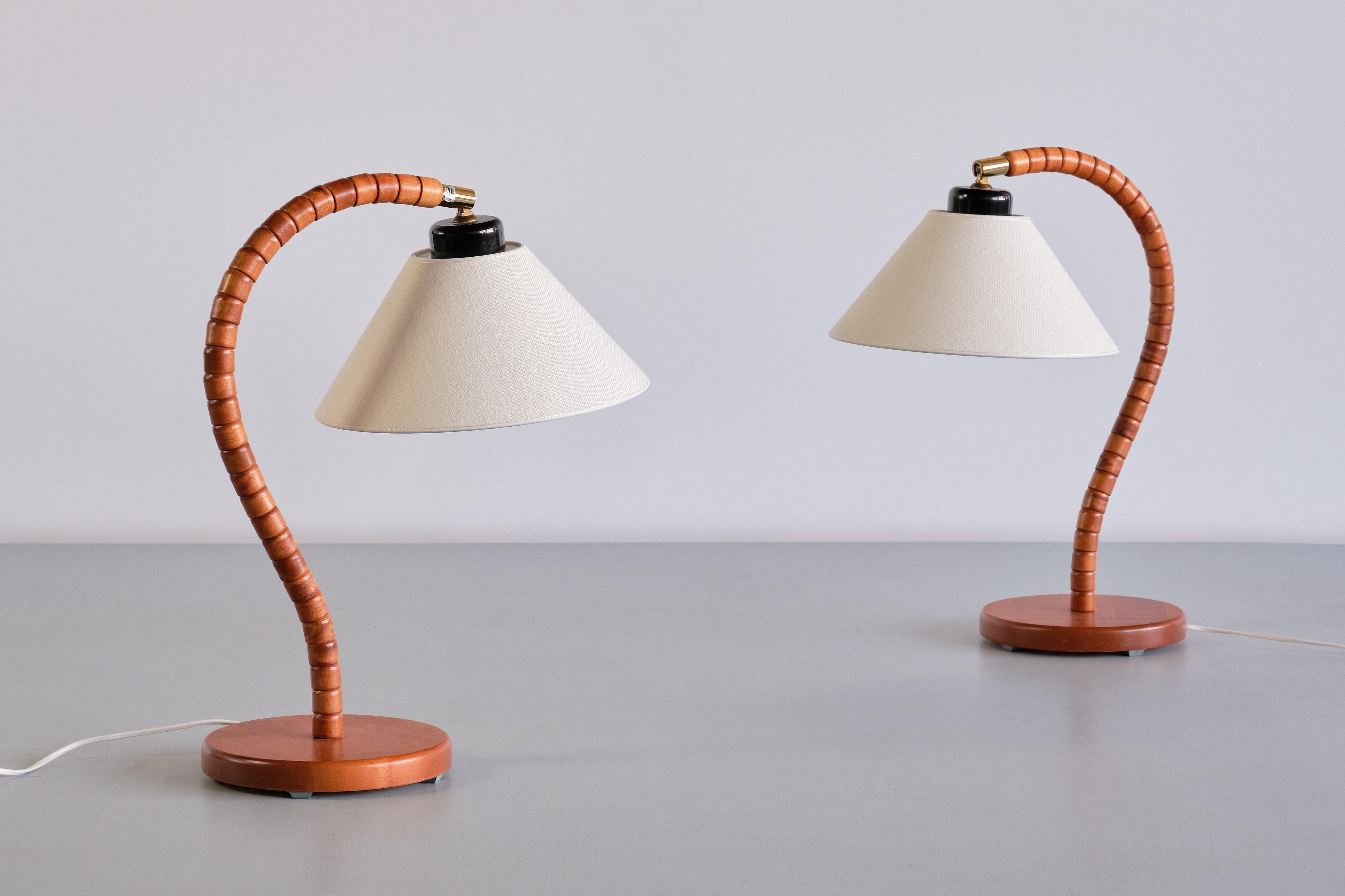 This striking pair of table lamps was produced by Markslöjd in Kinna, Sweden in the 1960s. The design is marked by the sculptural, organic shaped frame resting on a circular base. The base is made of solid stained beech wood. Brass and bakelite