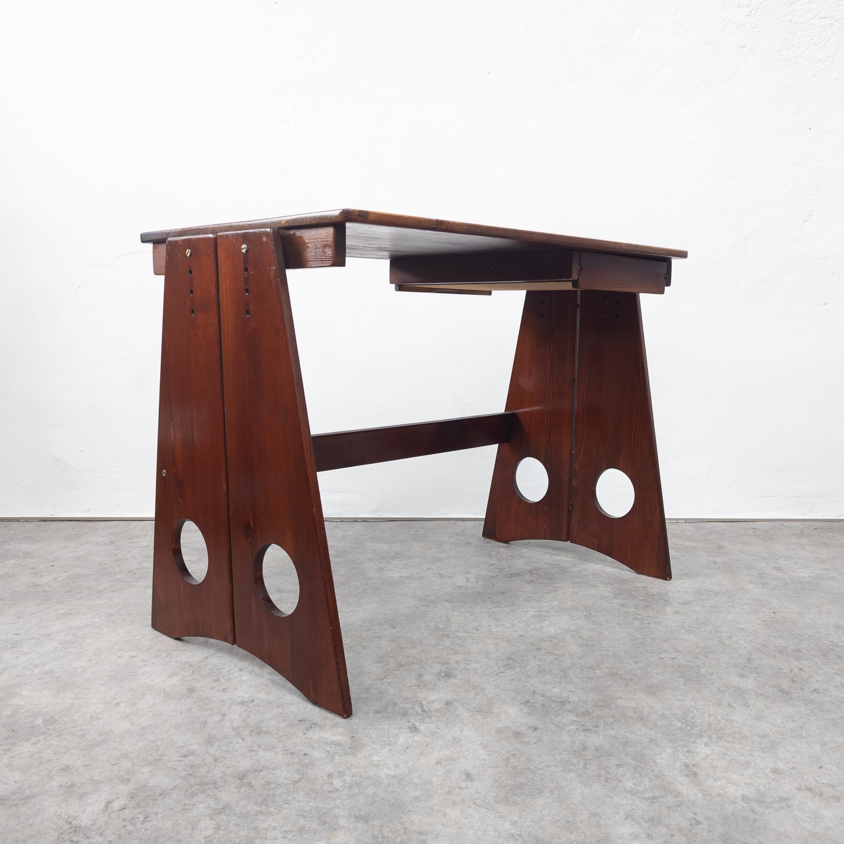 Rare pine wood desk designed by Gilbert Marklund. Manufactured by Furusnickarn AB, Sweden 1970s. Known for its iconic legs with circular perforations. Features a drawer underneath the table top, which can be accessed from both sides. Adjustable