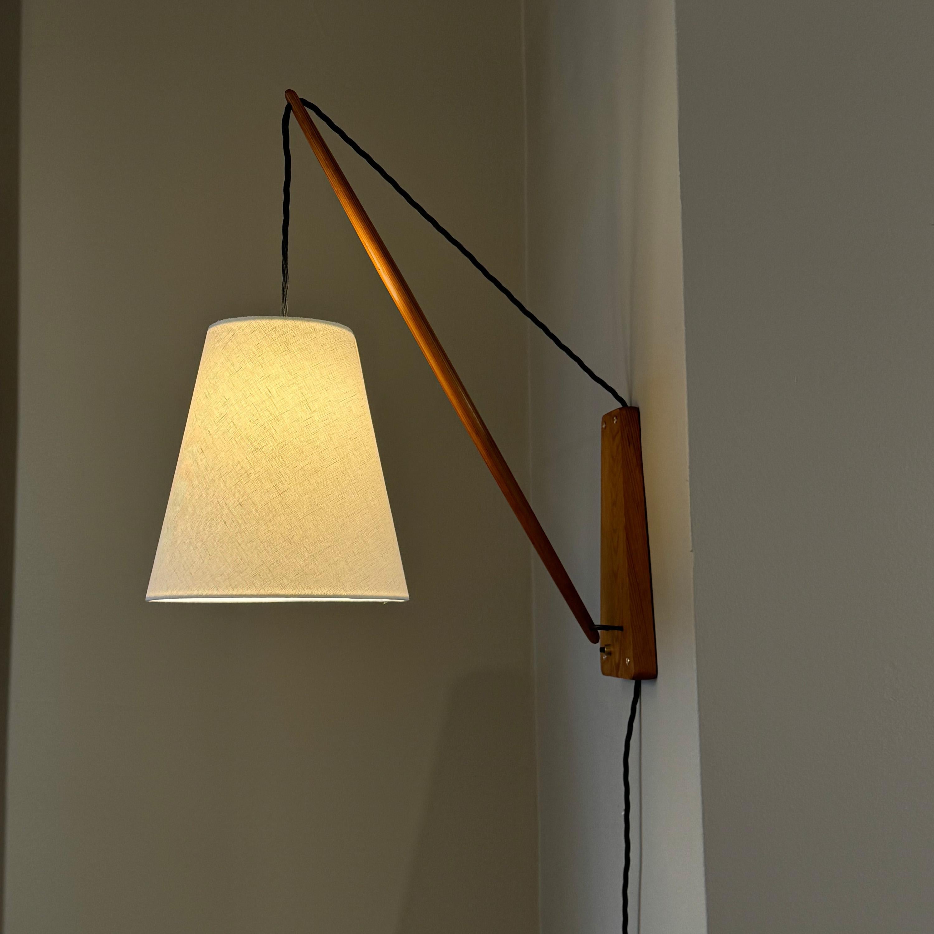 A pine wall light made in Denmark during the 1950s. 

Simple yet sculptural, this wall light is constructed from two main components: a trapezoid shaped wall plate which is connected to a cigar-shaped pine armature via a small metal component, which