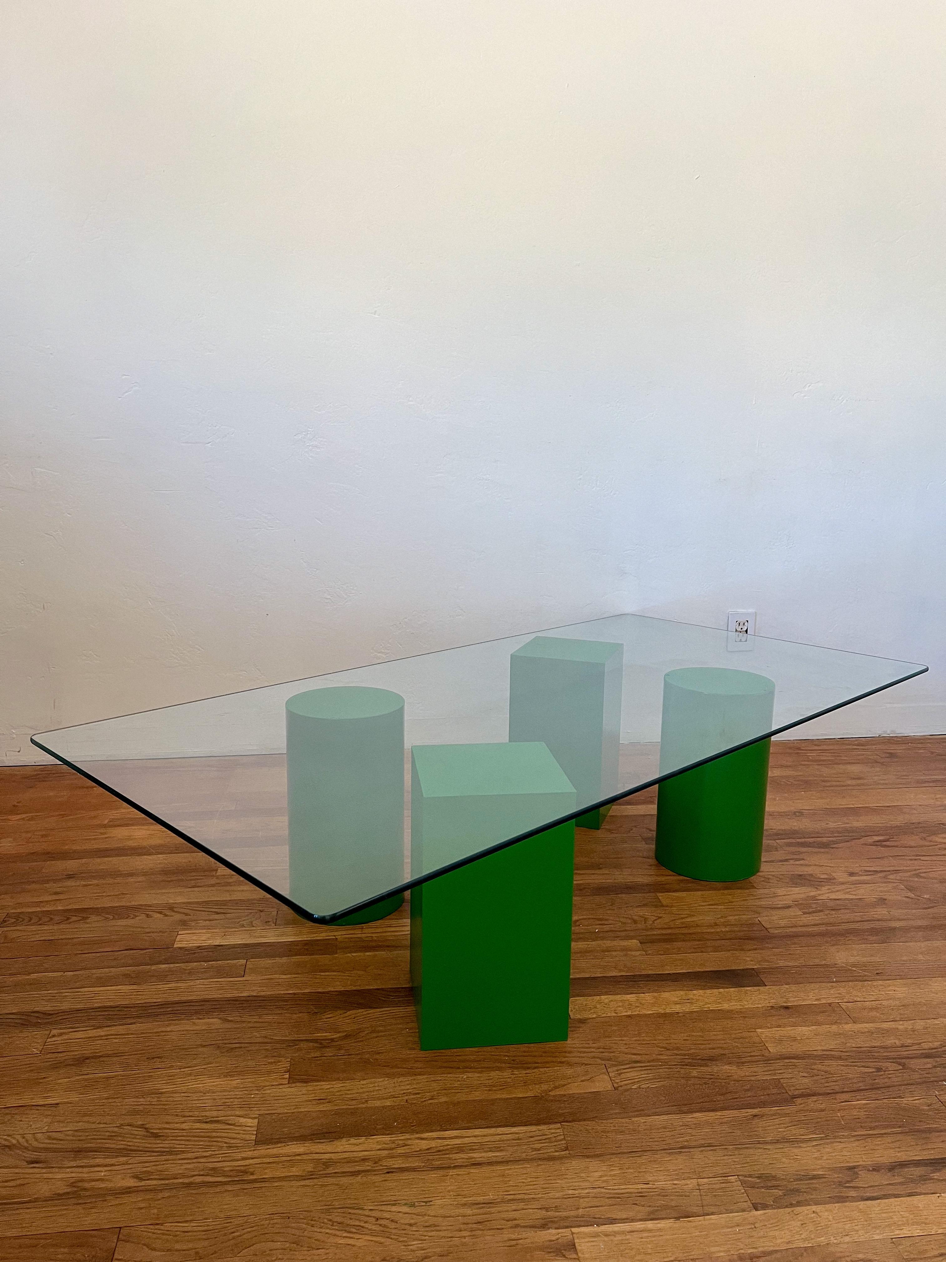 Vintage postmodern sculptural coffee table reminiscent of Lella & Massimo Vignelli designs. The table features four individual geometric pieces as a base for a glass top. The geometric pieces are finished in a striking emerald green, adding a bold,