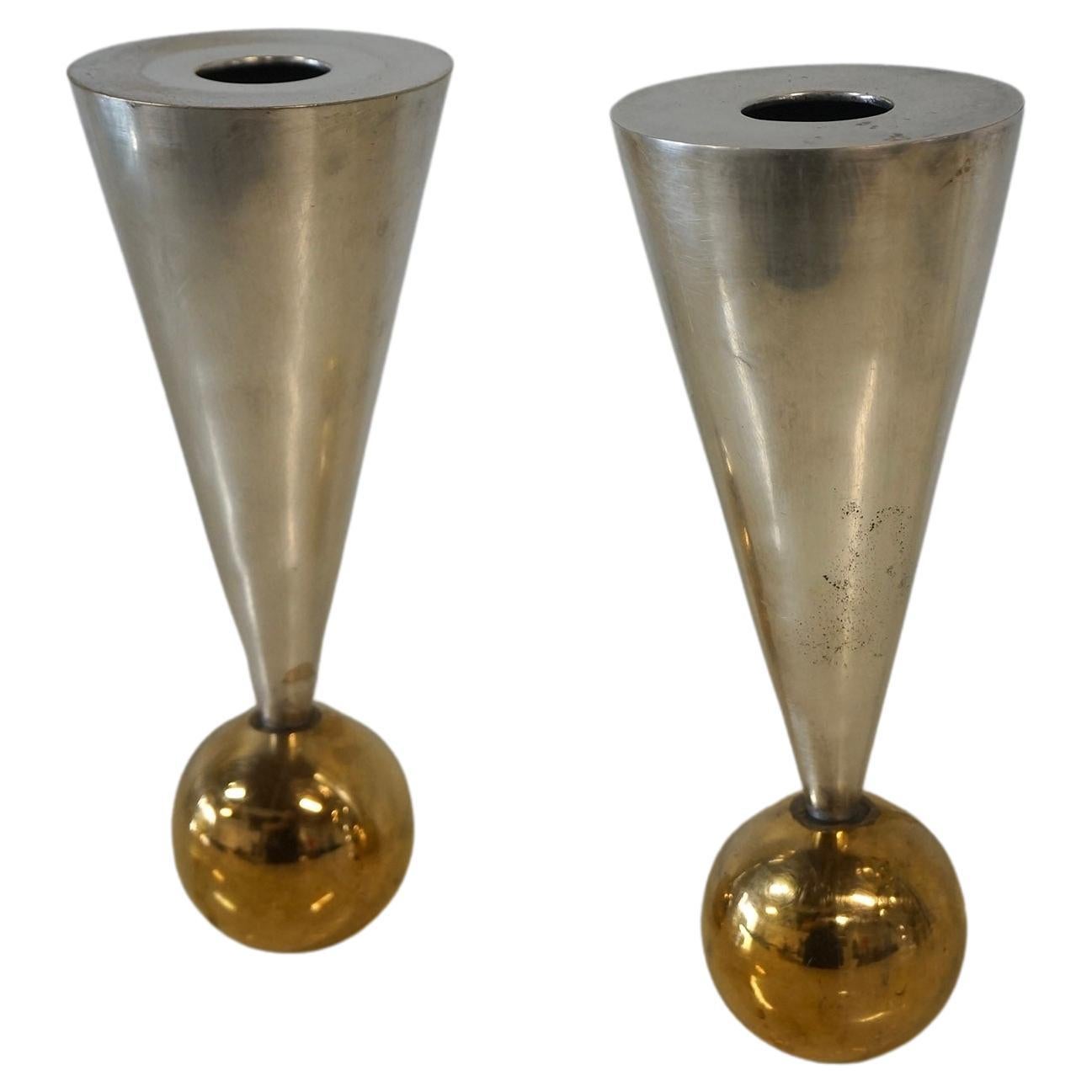 Striking Geometric Sculptural Postmodern Candle Holders in Silver and Brass Plated made in the 1980s. The silver body of the candle holder is triangular and it has a round brass plated ball shaped base. There’s an opening at the top for placement of