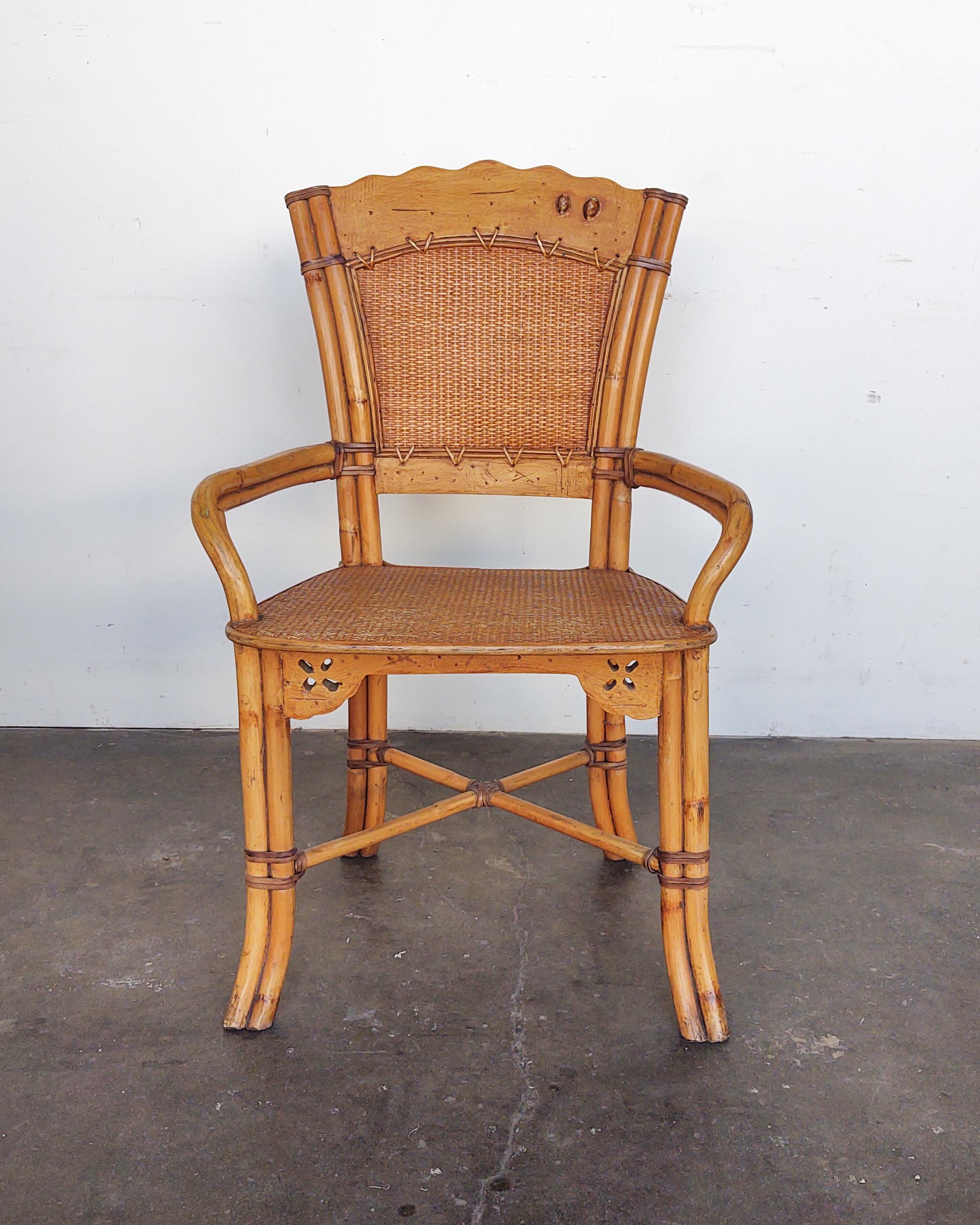 Sculptural rattan arm chair with scalloped back rest. Framed piece of woven cane on backrest with an inlay of two cowrie shells. 

Measures: 23.5