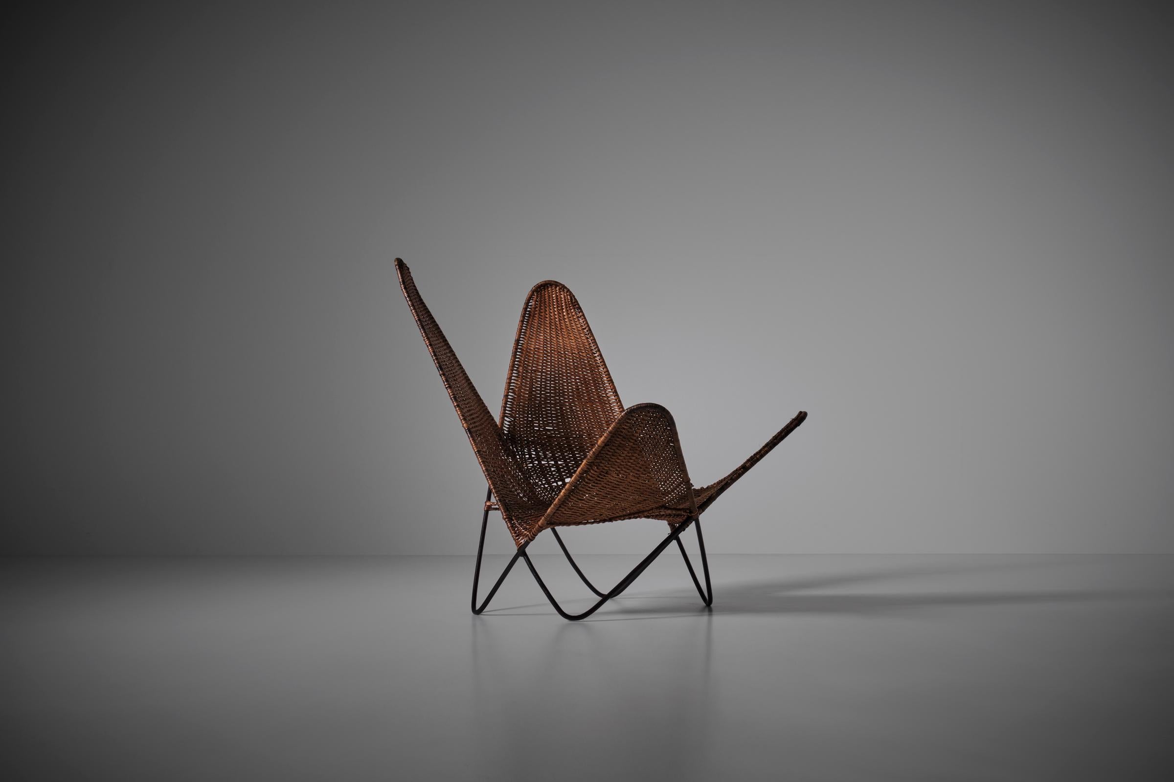 Exceptional rattan butterfly chair, France 1960s. Sculptural lounge chair with an interesting contrast in materials and textures between the thin black metal wire framing and the crafted woven rattan seat. The chair is in a very good and strong