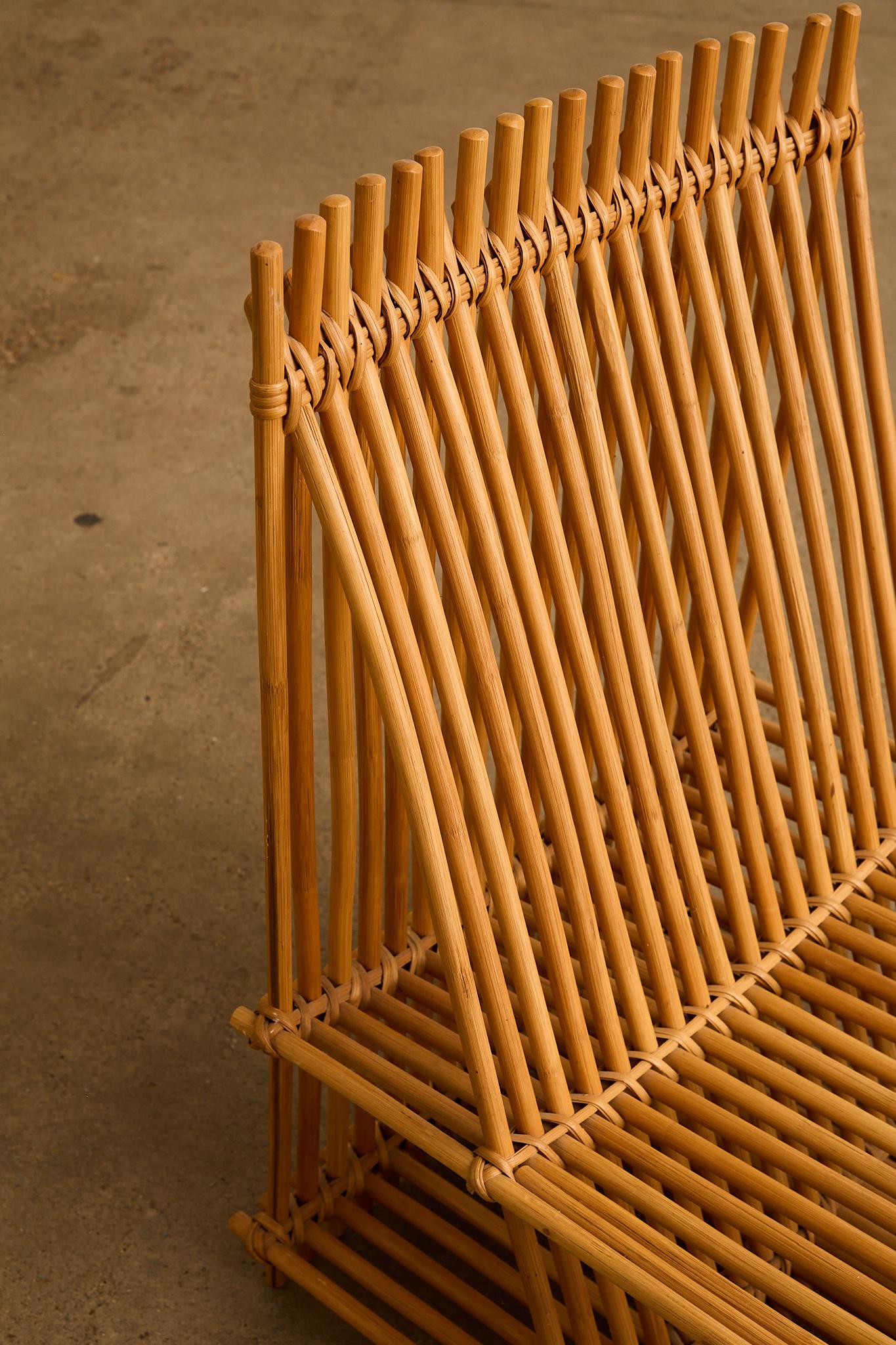 Scultorea coppia di poltroncine in rattan, formate da canne disposte ritmicamente che creano uno schienale e una seduta grafici e aperti. La calda tonalità miele e il profilo geometrico gli conferiscono una presenza leggera e architettonica in una