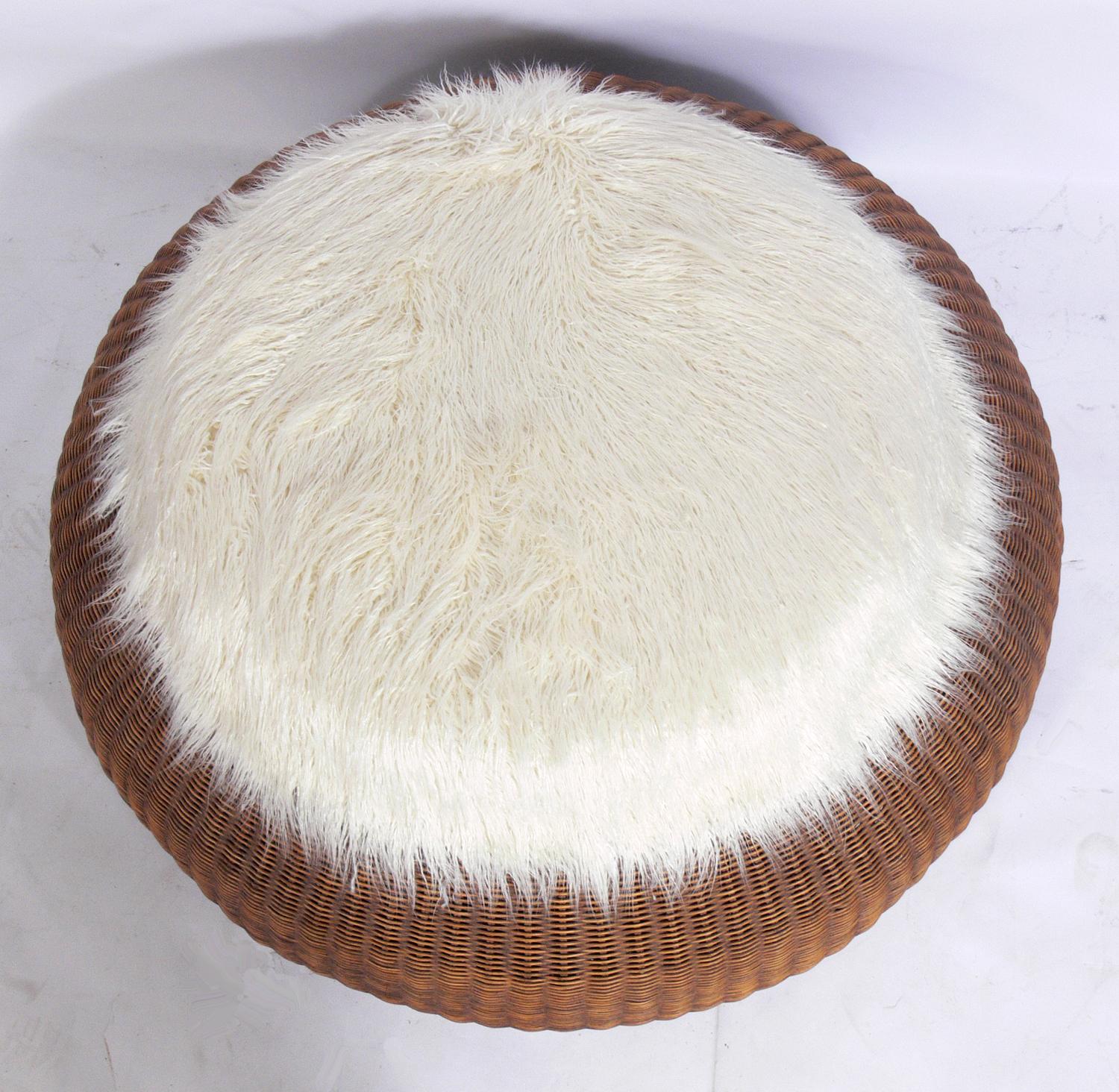 Sculptural rattan ottoman, in the manner of Isamu Kenmochi, circa 1960s. It retains its warm original patina. It has been recently reupholstered in a plush faux Mongolian sheepskin.