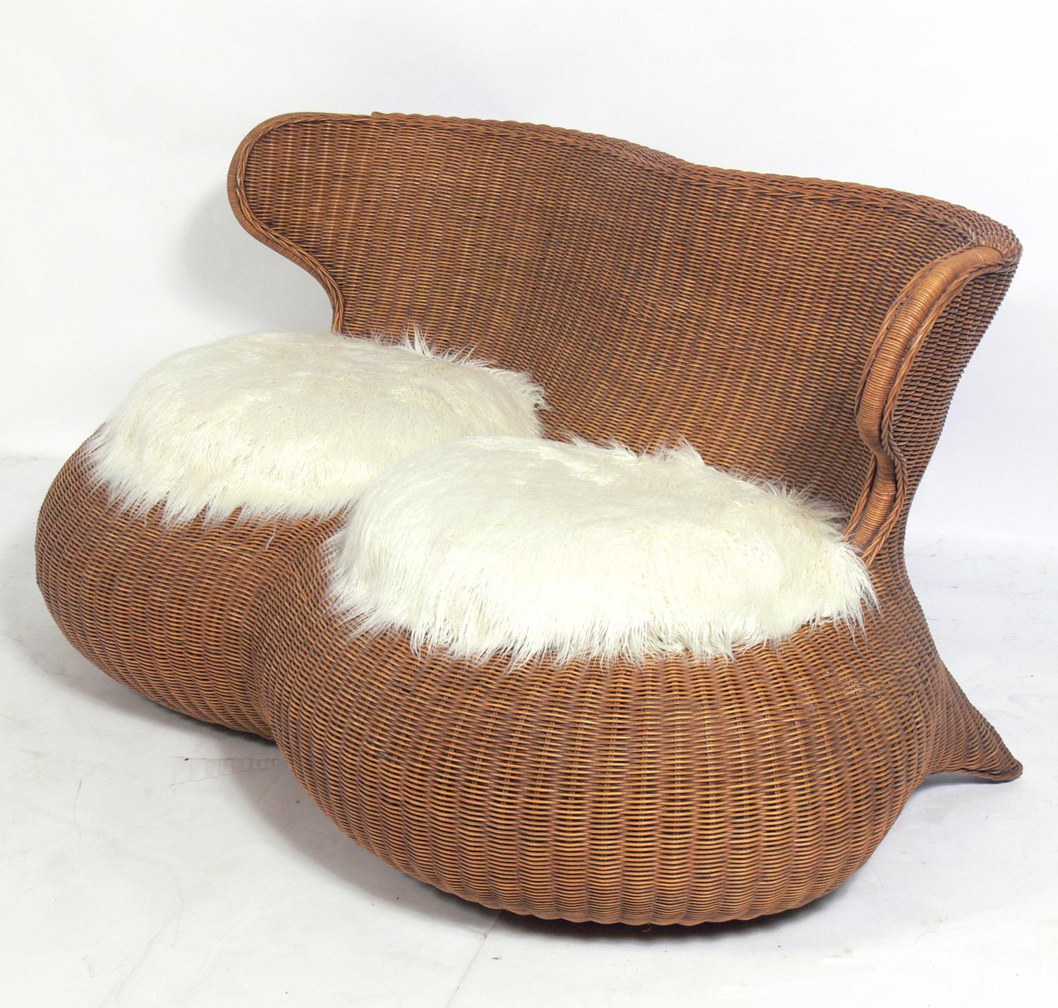 Sculptural Rattan Settee, in the manner of Isamu Kenmochi, circa 1960s. It retains it's warm original patina. It has been recently reupholstered in a plush faux mongolian sheepskin.
