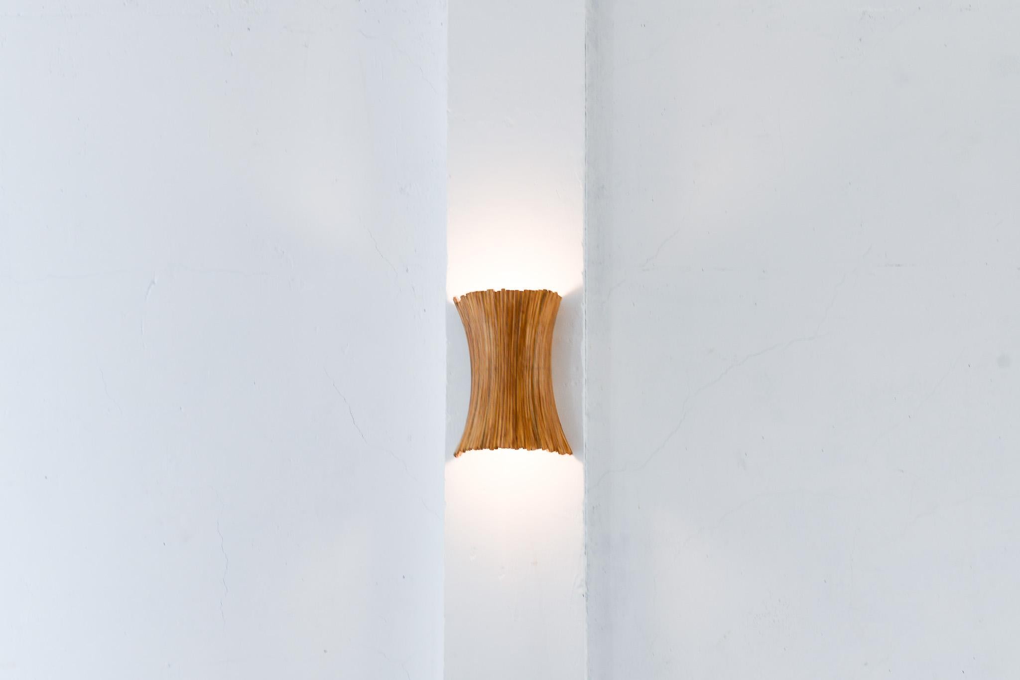 Introducing the one-of-a-kind sculptural rattan wall sconce, handcrafted with care to achieve beautiful curves yet organic finish. Made from natural pencil reed rattan, this sconce adds a unique and natural touch to any space. Expertly crafted for a