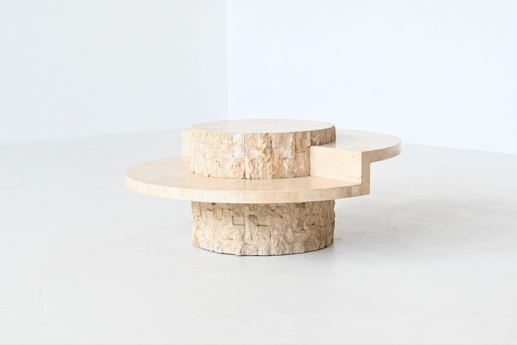 Beautiful sculptural round coffee table, Belgium 1970. The top is made of highly polished cream white Mactan stone supported by a signature textured carved stone tile base. This table offers a sculptural centrepiece for your home with its step level