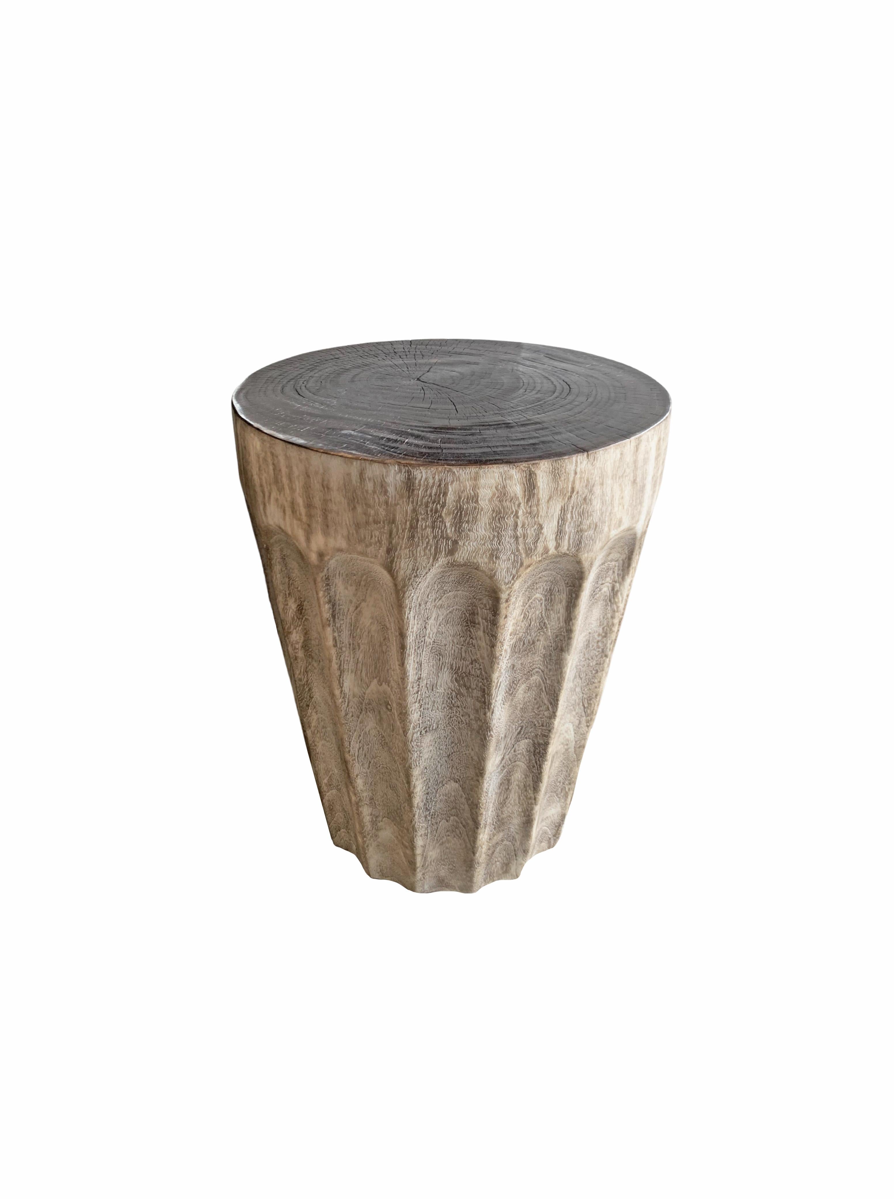 This wonderfully sculptural round side table features a ribbed pattern along its sides. It's narrow slender shape and mix of curves adds to its charm. The table's neutral pigment makes it perfect for any space. A uniquely sculptural and versatile
