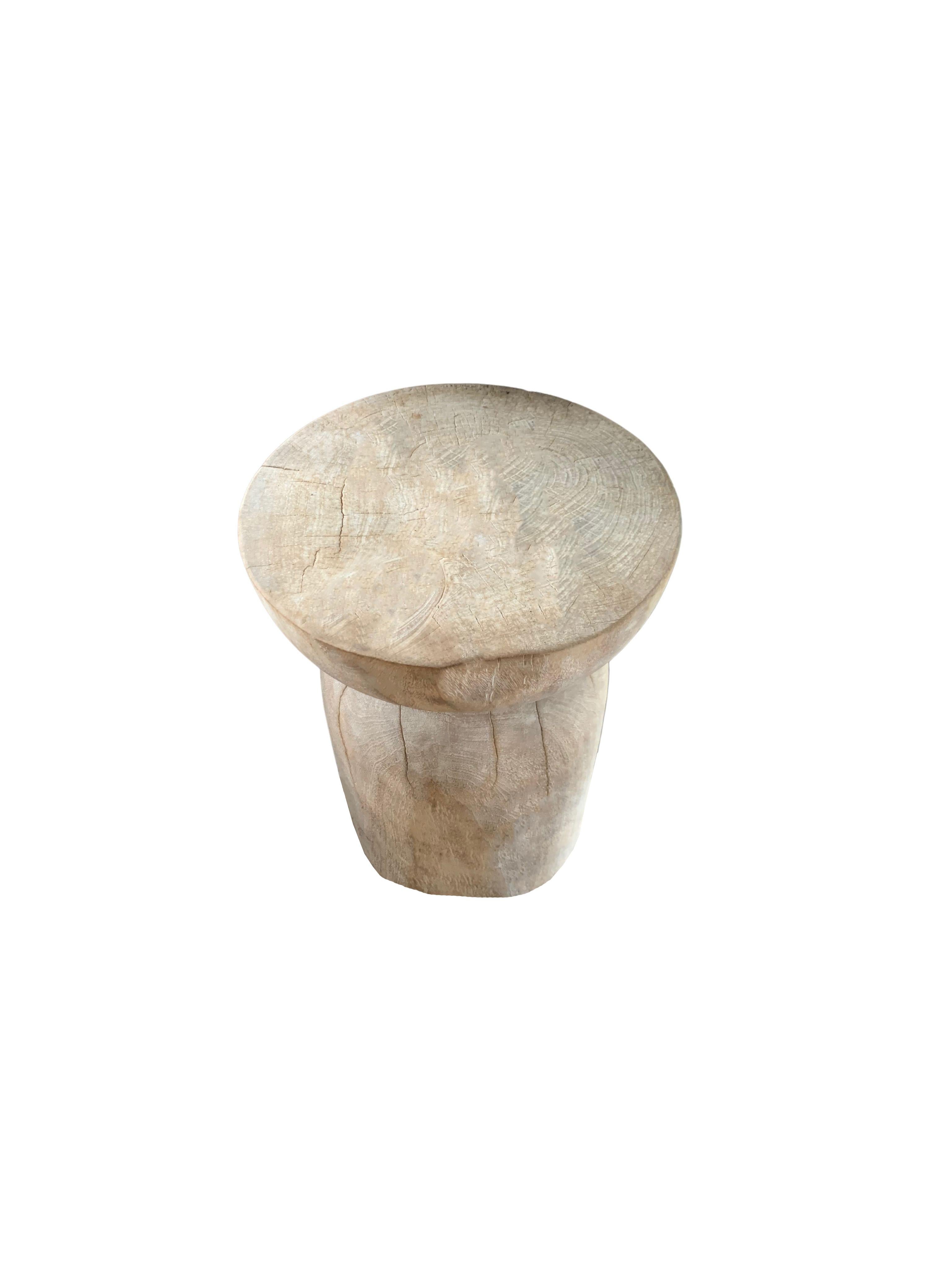 A wonderfully sculptural round side table. The table's neutral pigment makes it perfect for any space. It was crafted from a solid block of mango wood. It features a sanded down finish exposing a wonderful mix of wood textures. The shades of white