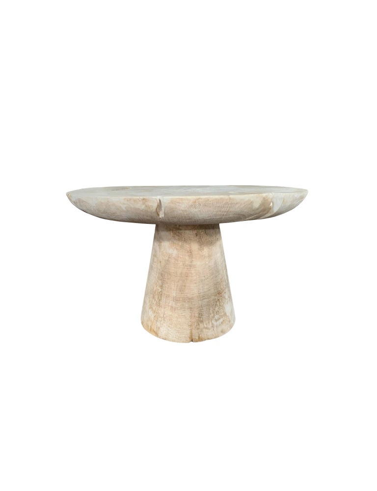 A wonderfully sculptural round side table with a bleached finish. Its neutral pigment and wood texture makes it perfect for any space. It features a tapered base and large round table top. A uniquely sculptural and versatile piece certain to invoke