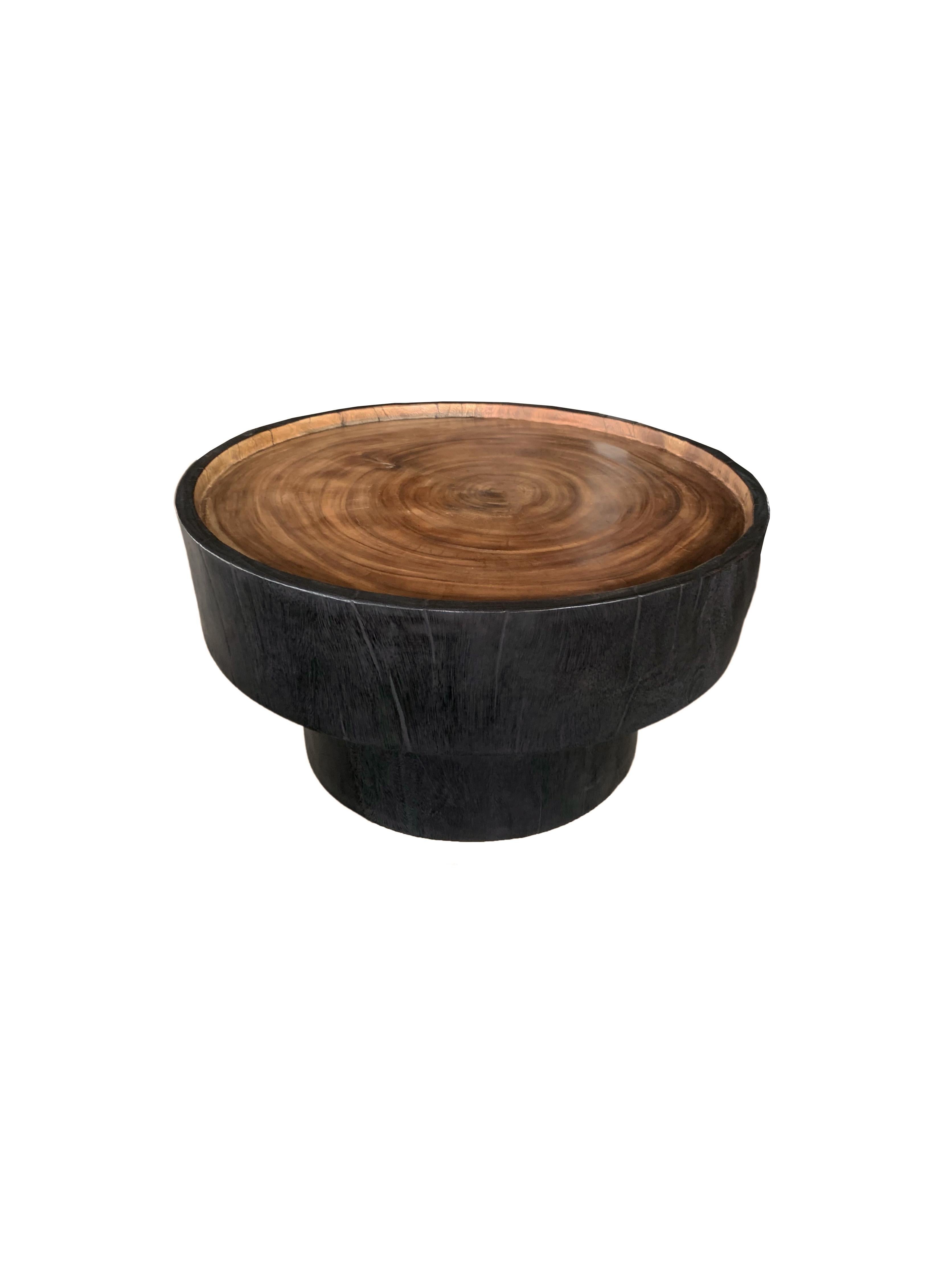 A wonderfully sculptural round side table. Its neutral pigment and subtle wood texture makes it perfect for any space. A uniquely sculptural and versatile piece. This table was crafted from mango wood and has a smooth texture. It features a contrast
