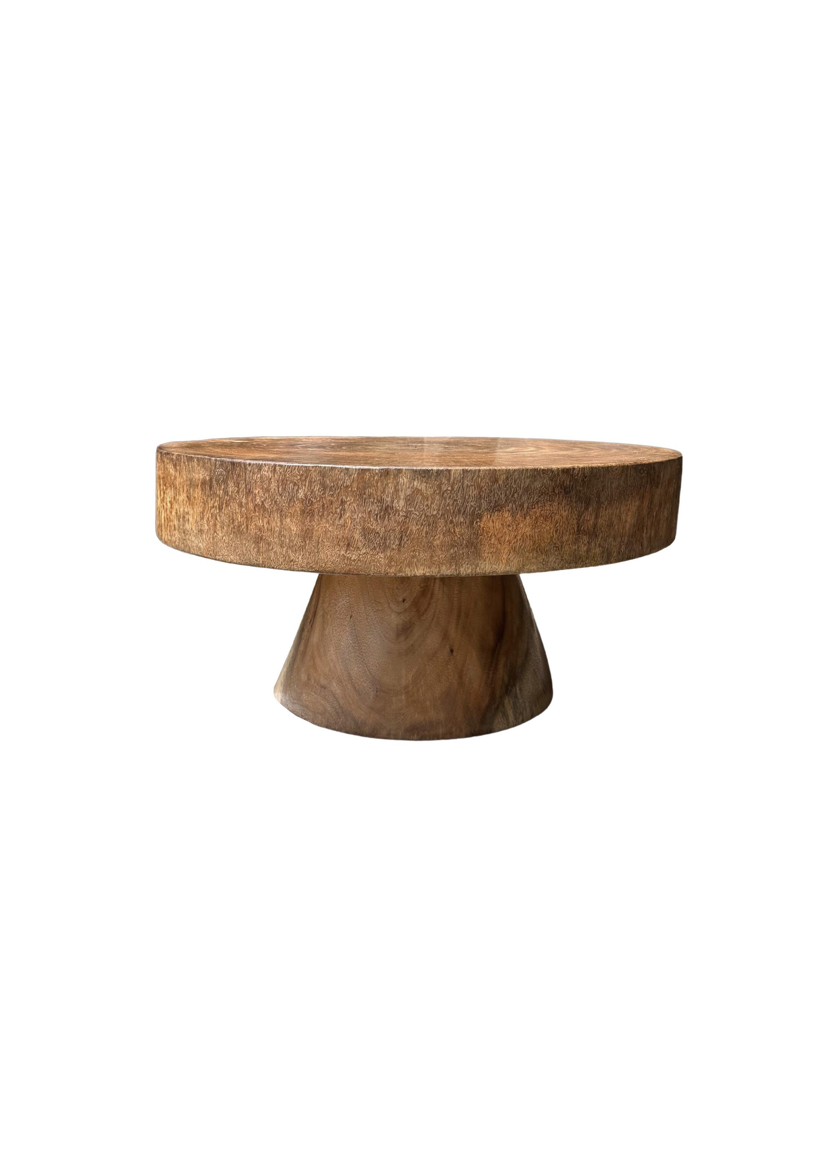 A wonderfully sculptural round side table featuring a natural finish. Its neutral pigment and subtle wood texture makes it perfect for any space. A uniquely sculptural and versatile piece certain to invoke conversation. This table was crafted from