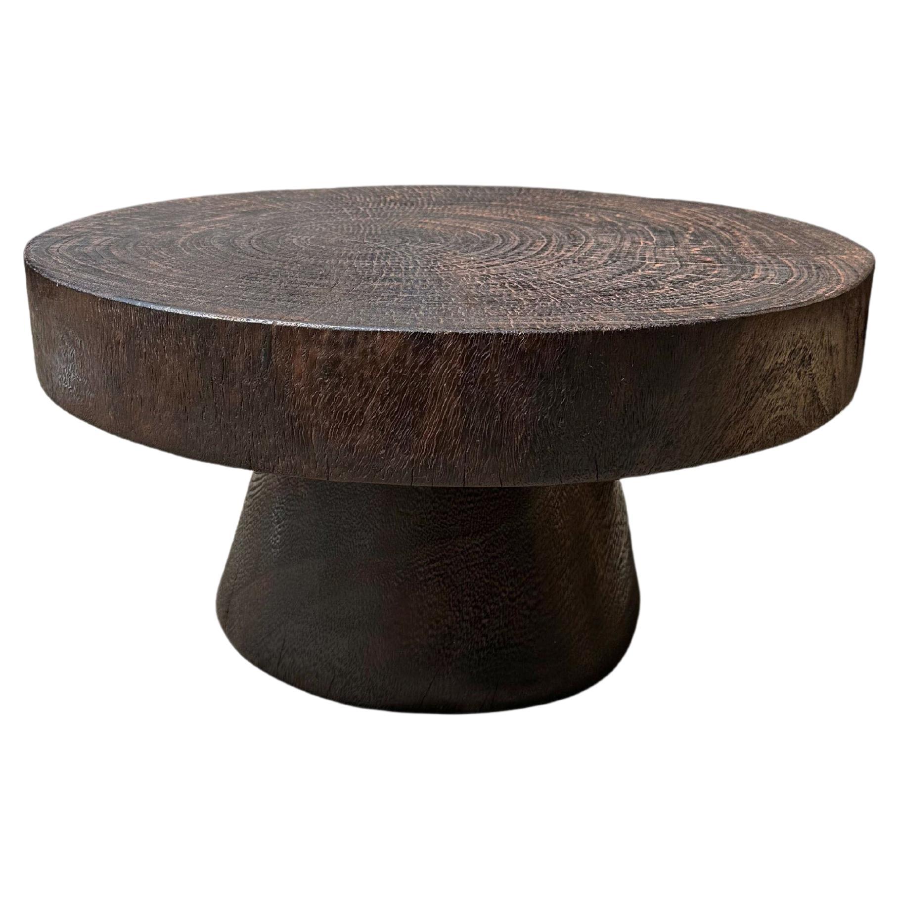 Table ronde sculpturale fabriquée en bois de poirier massif, finition naturelle