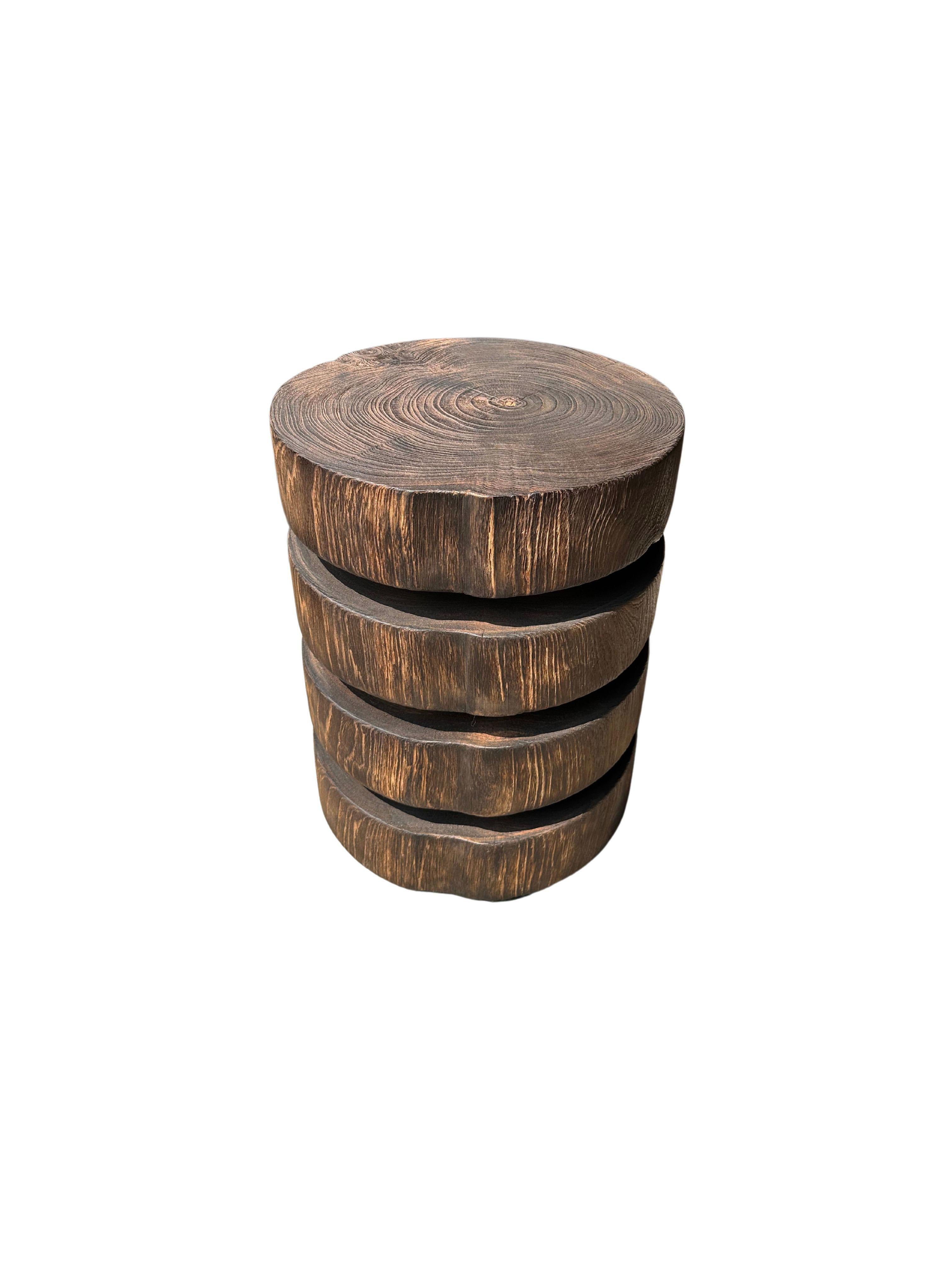 A wonderfully sculptural round side table featuring a natural finish. Its neutral pigment and subtle wood texture makes it perfect for any space. This table was crafted from solid suar wood, made to resemble stacked slabs of suar wood this table was
